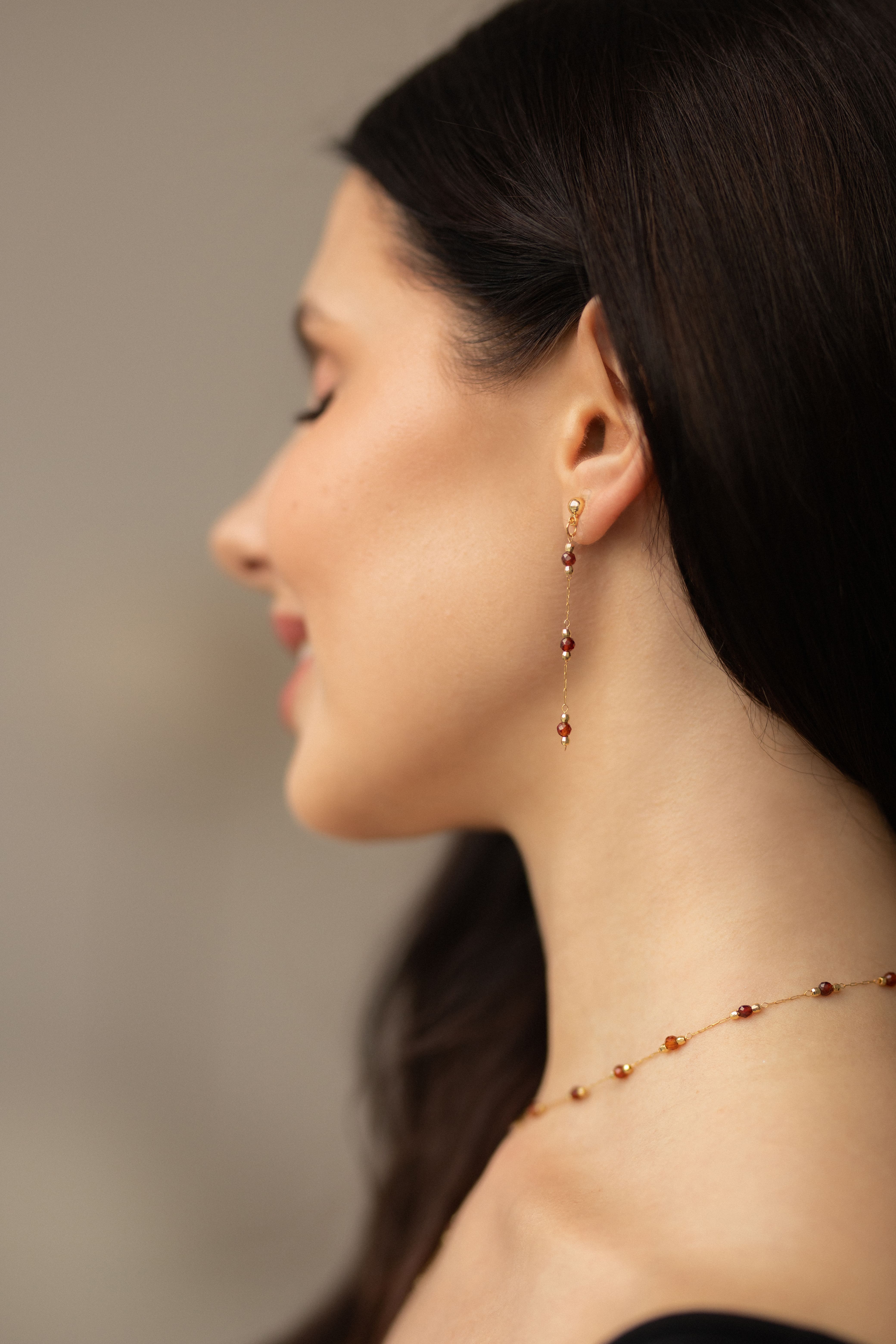 Elegant gold-plated brass lariat necklace with genuine natural garnet stones and matching dainty garnet stud earrings, creating a refined and timeless jewelry set perfect for everyday wear or special occasions.
