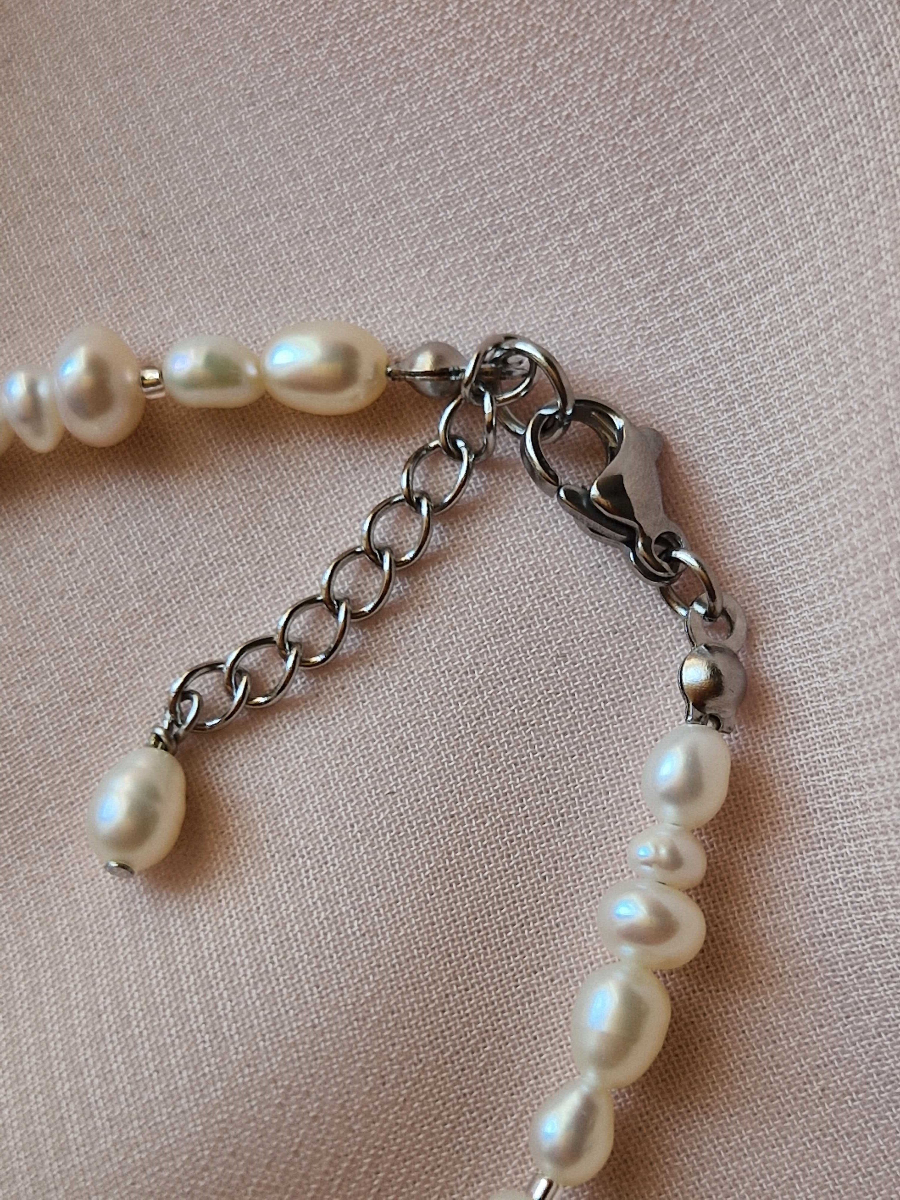 Pearl bracelet with a silver clasp on a light pink background