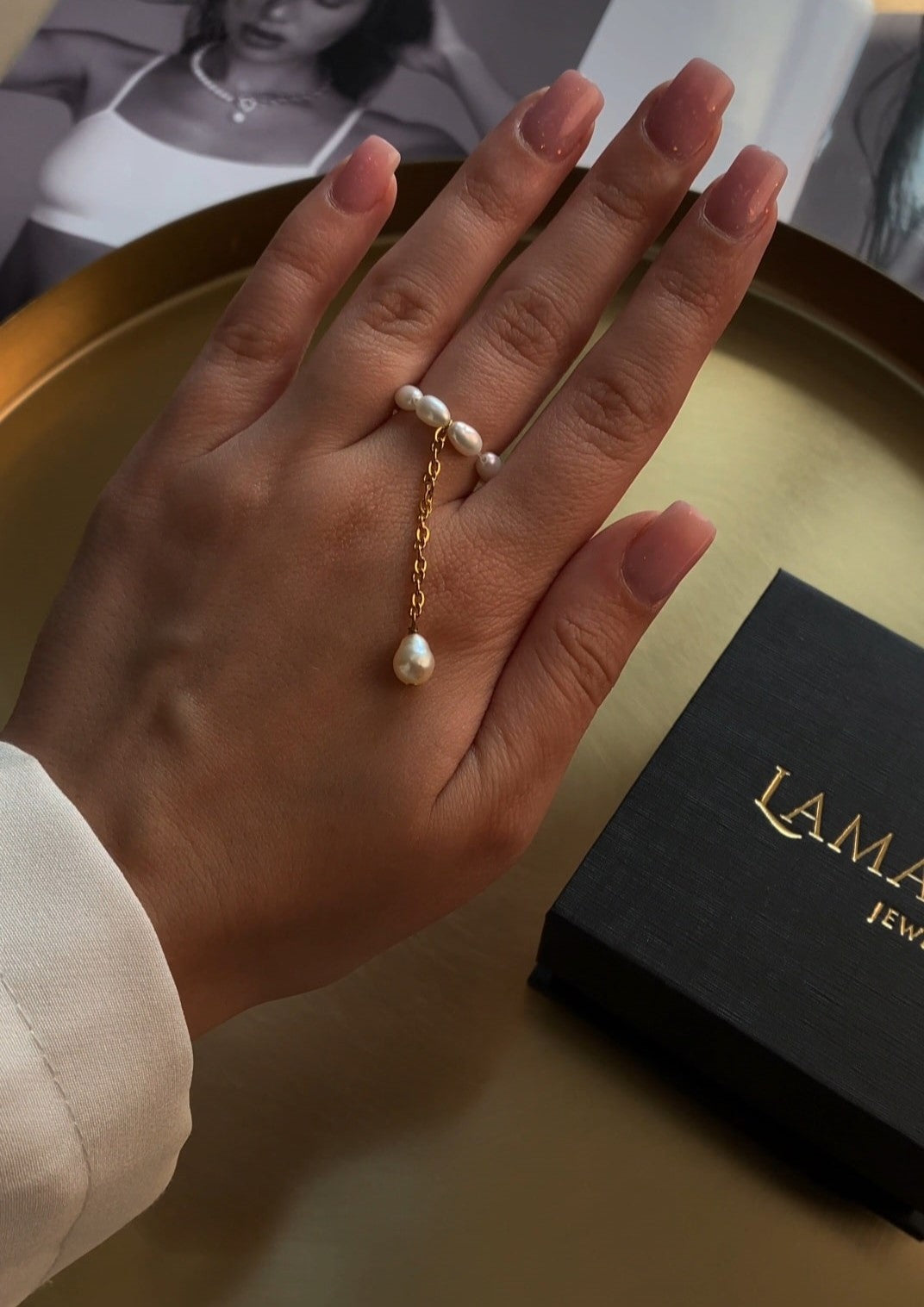 Delicate gold-tone ring featuring natural freshwater rice pearls paired with a fine chain, combining minimalist design with elegant femininity.