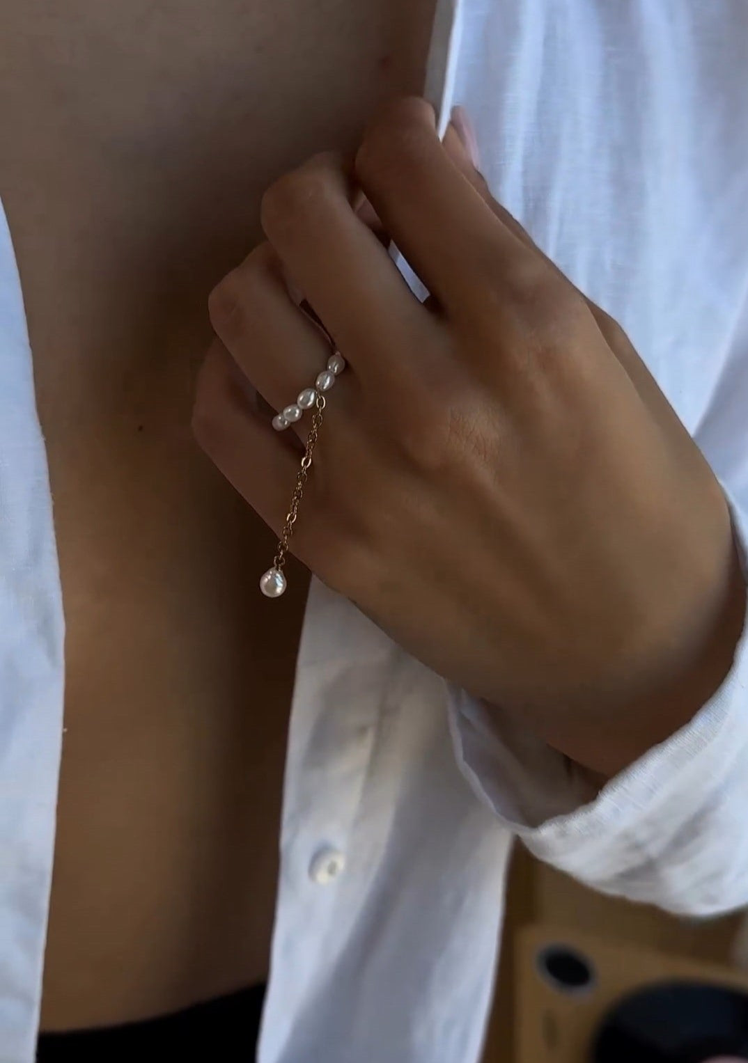 Delicate gold-tone ring featuring natural freshwater rice pearls paired with a fine chain, combining minimalist design with elegant femininity.