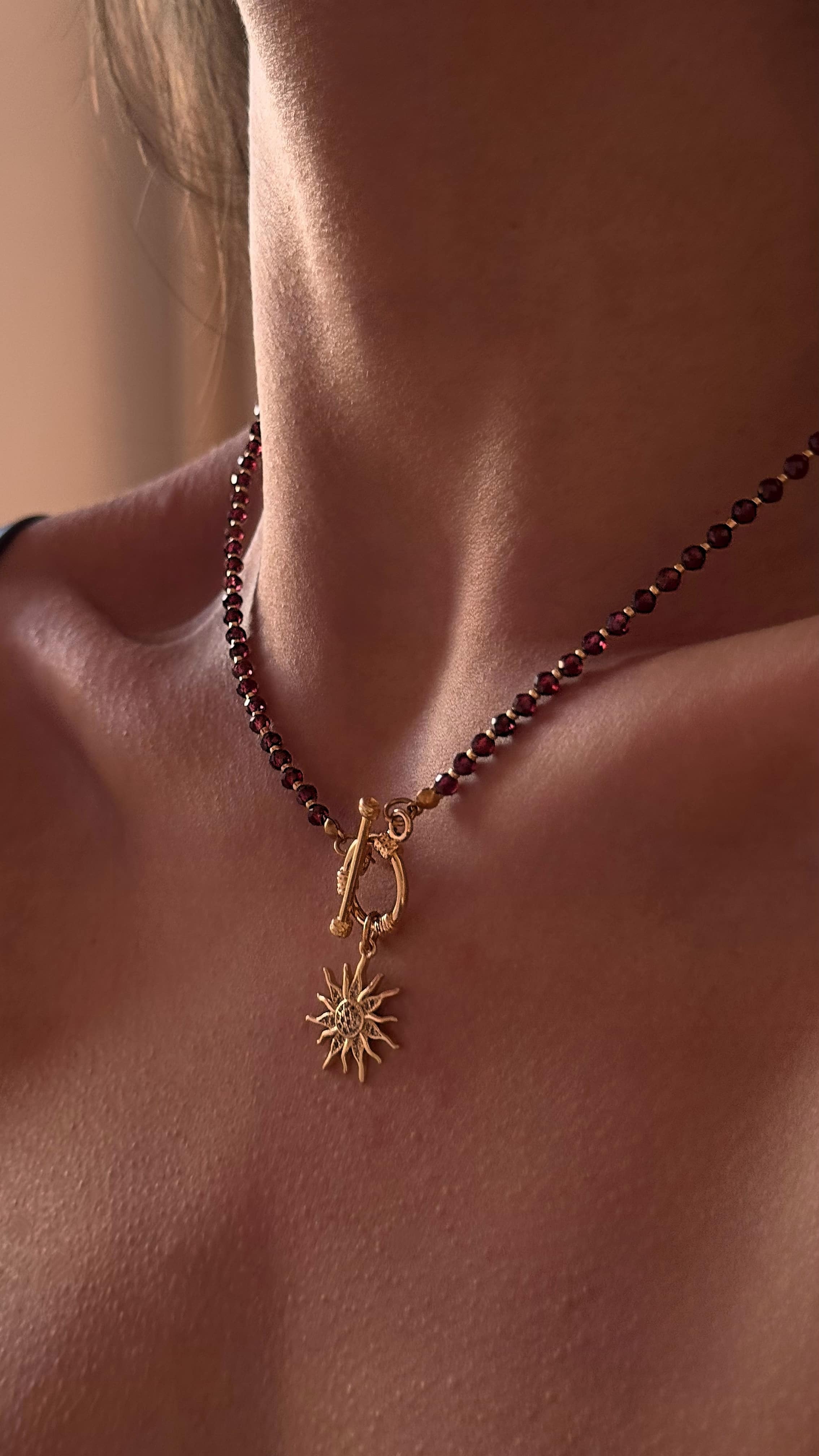 Elegant necklace featuring natural garnet stones, premium Japanese seed beads, and a sparkling sun-shaped pendant adorned with cubic zirconia, blending gemstone charm with celestial elegance.
