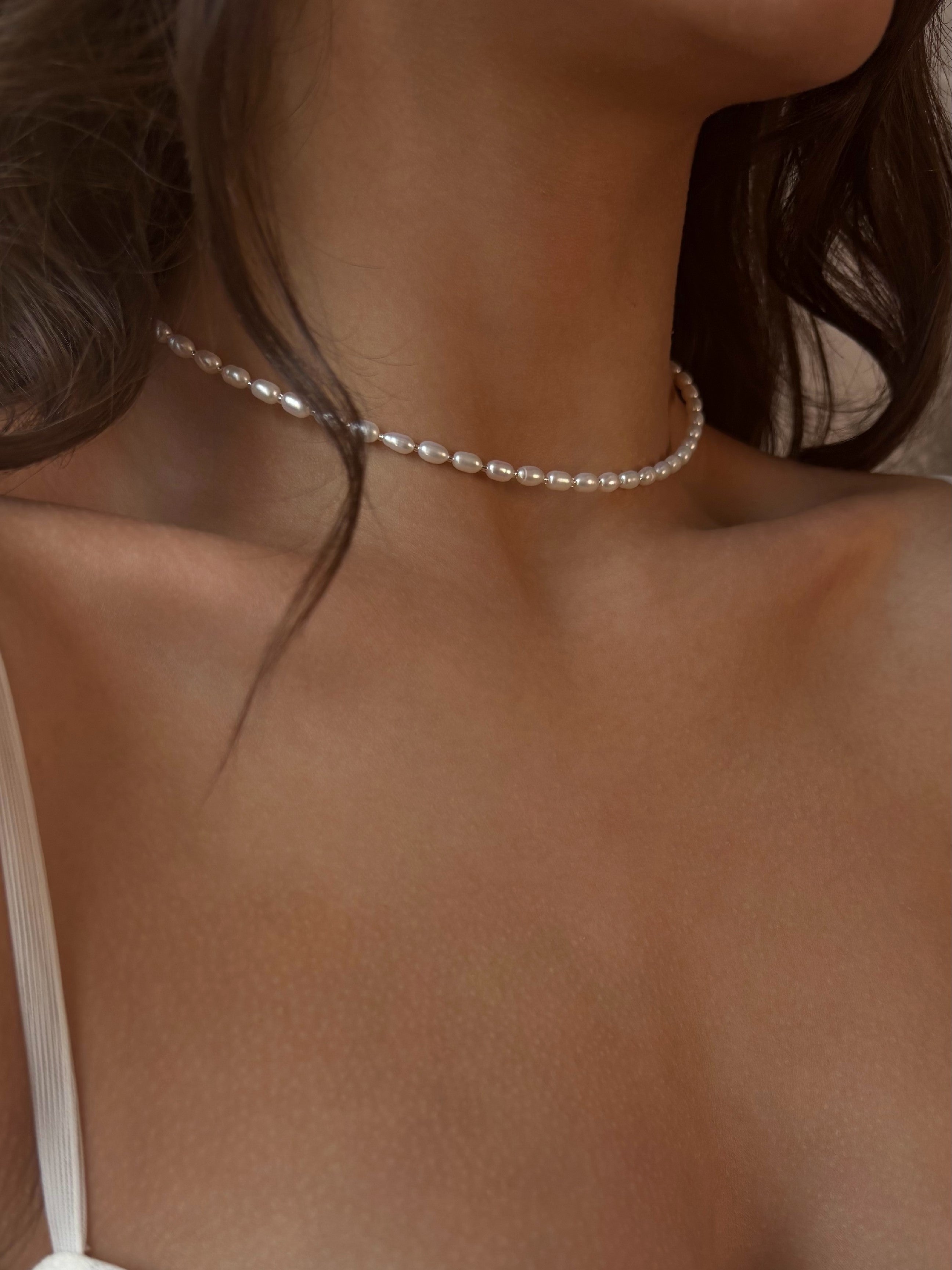 Pearl choker necklace worn by a person with a blurred background