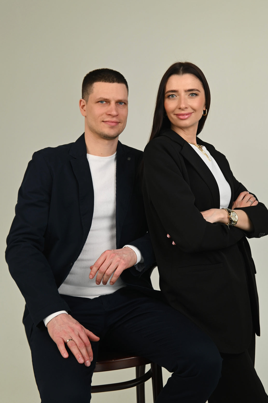 Two people in formal attire sitting on a plain background
