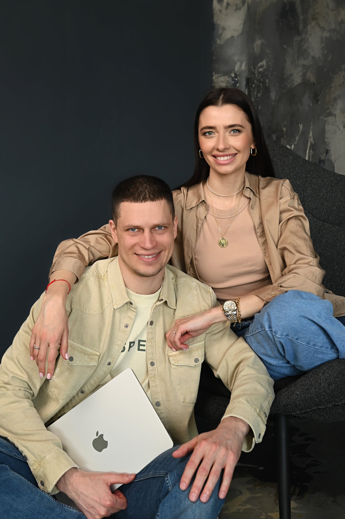 Two people sitting together on a couch with a dark background