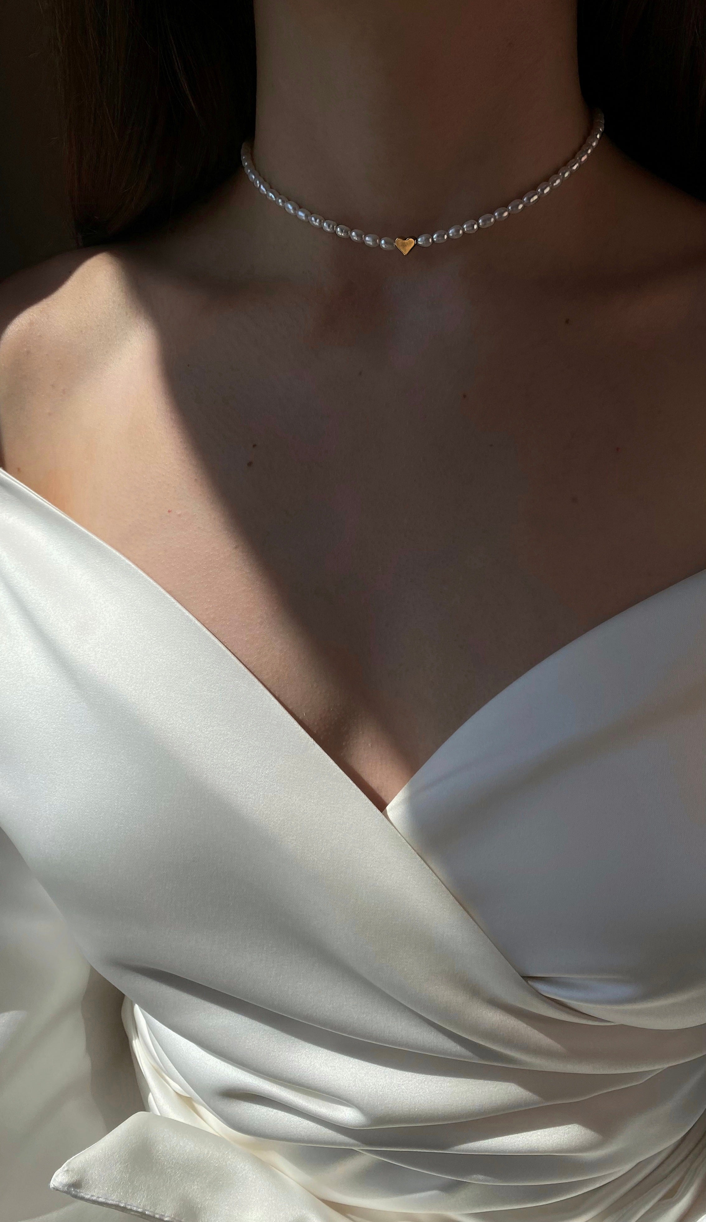 Natural pearl choker with radiant freshwater pearls and a dainty gold-tone heart charm, offering a minimalist and elegant look perfect for everyday wear or special occasions.