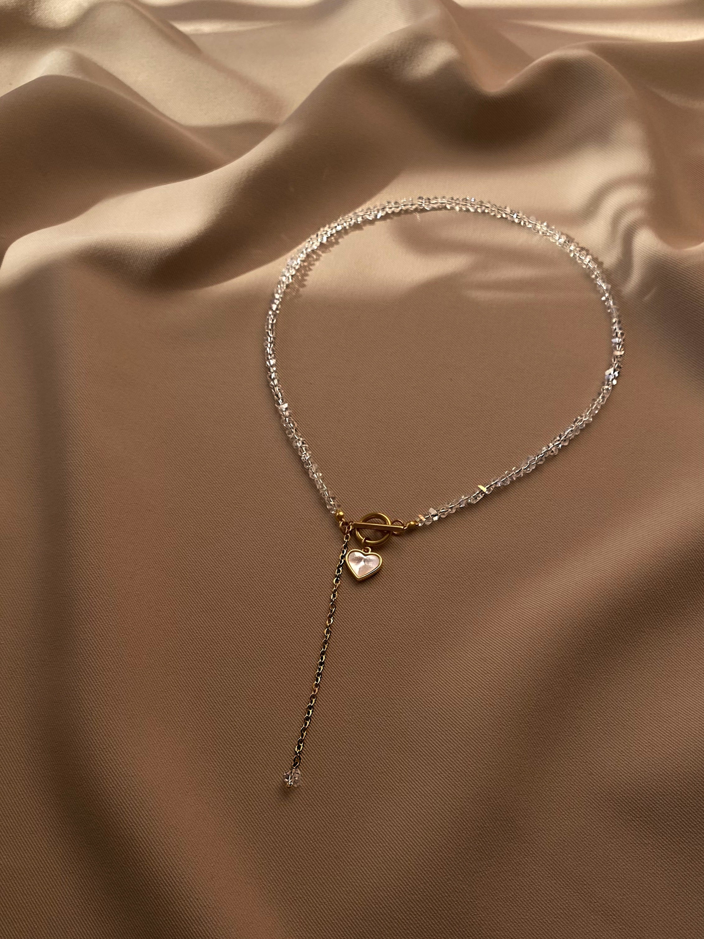 Delicate necklace with a heart pendant on a beige fabric background