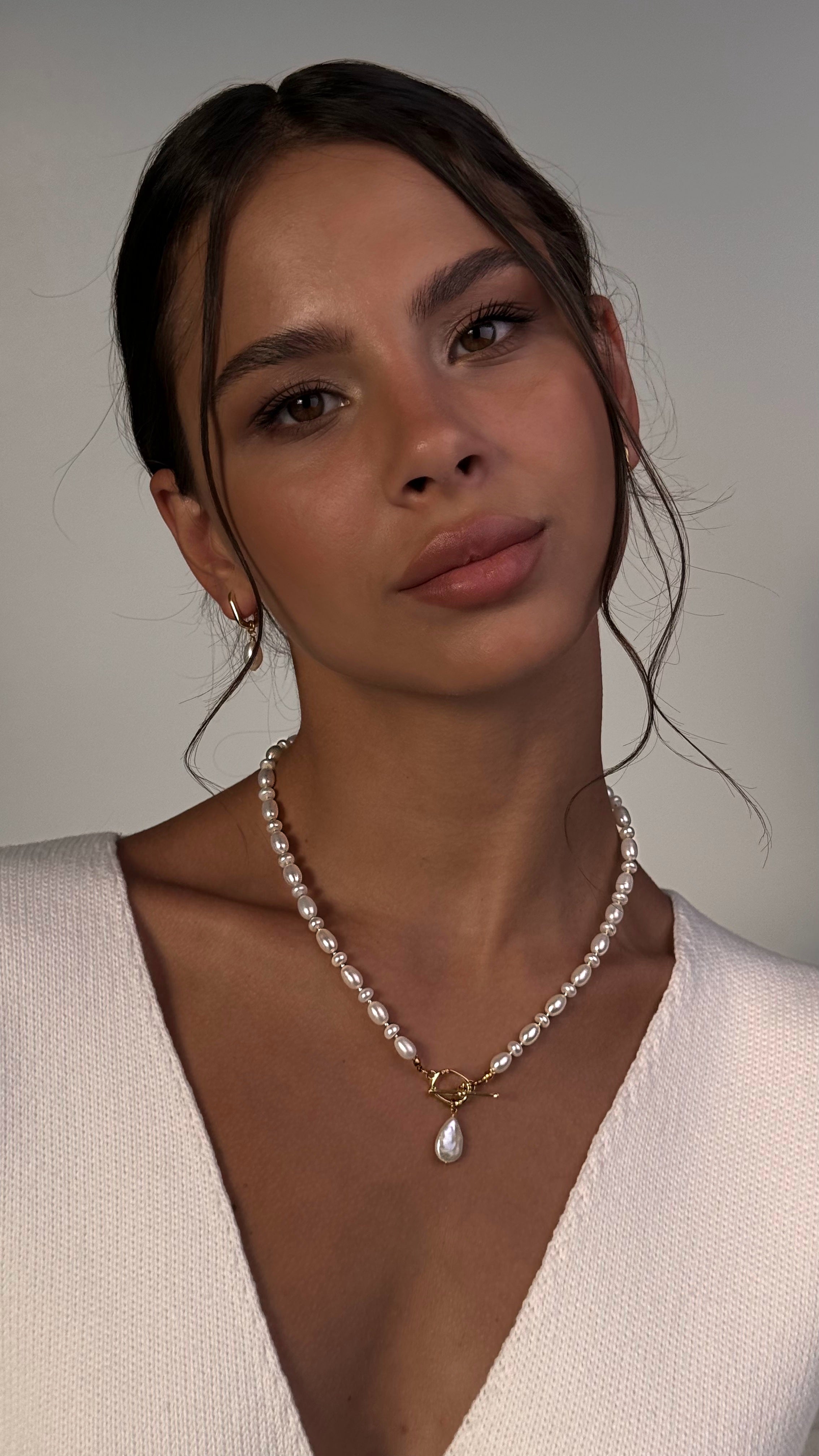 Woman wearing a pearl necklace against a neutral background