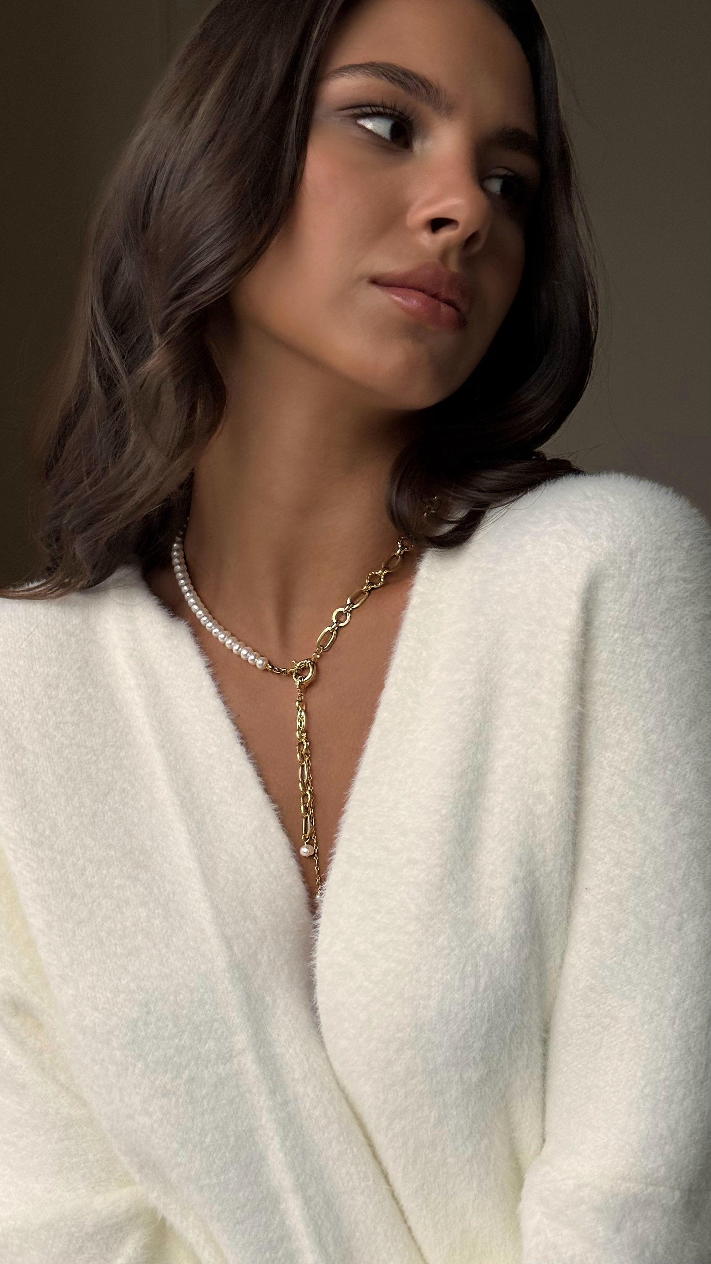 Woman wearing a gold-plated necklace with a plain background