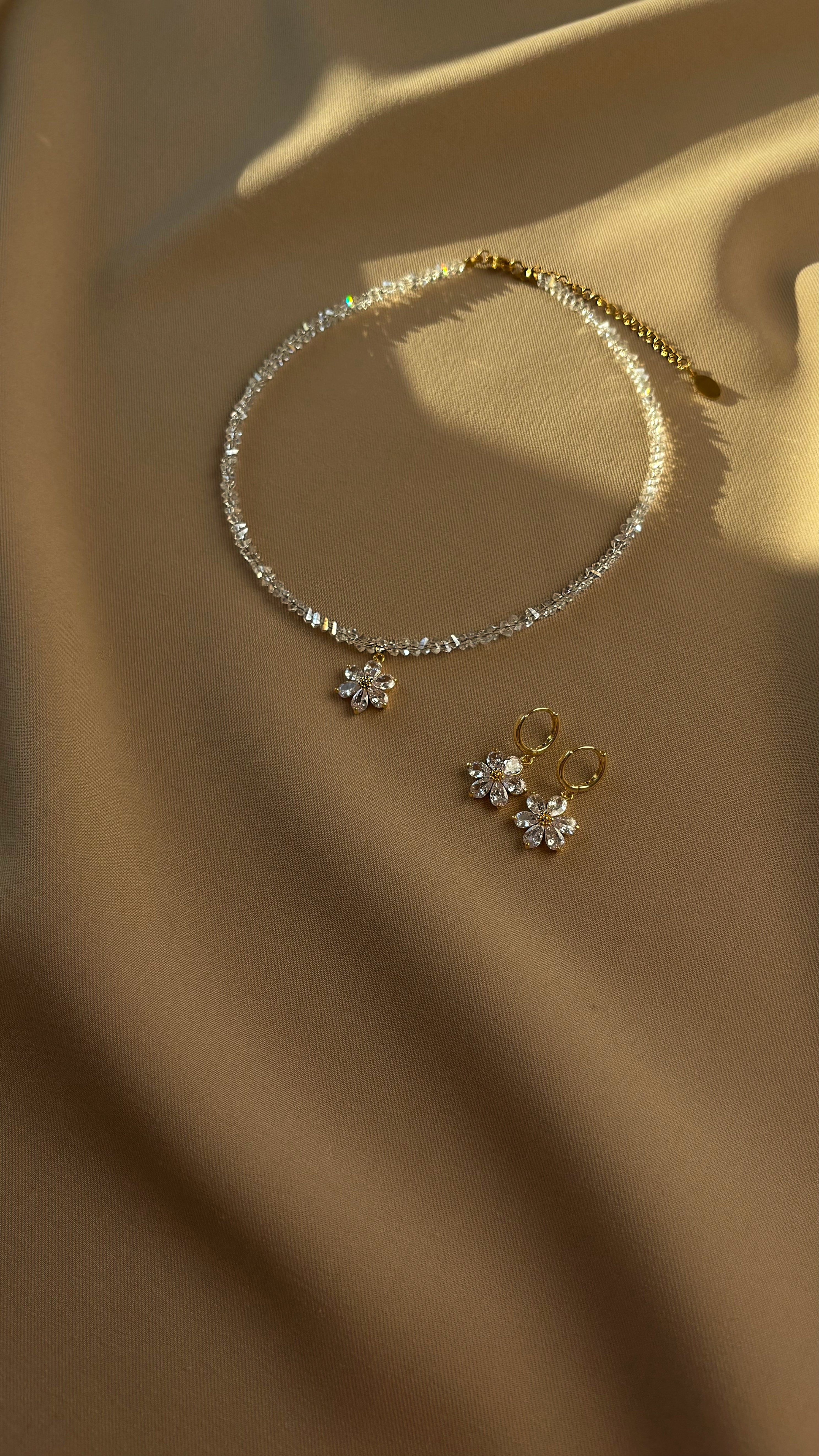 Clear crystal choker with floral charms on a beige fabric background
