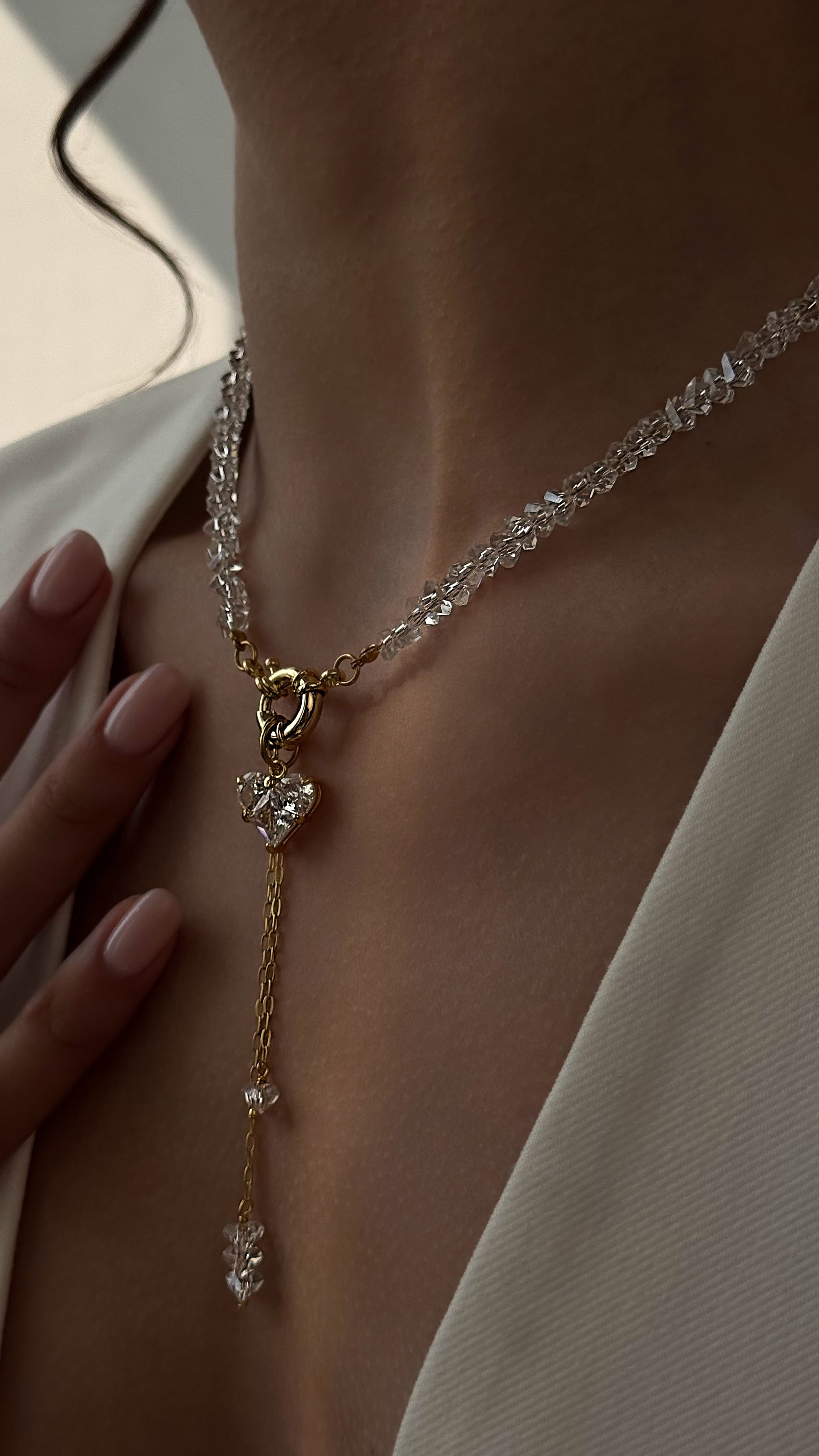 Delicate gold-plated necklace with crystals on a person wearing a white garment.