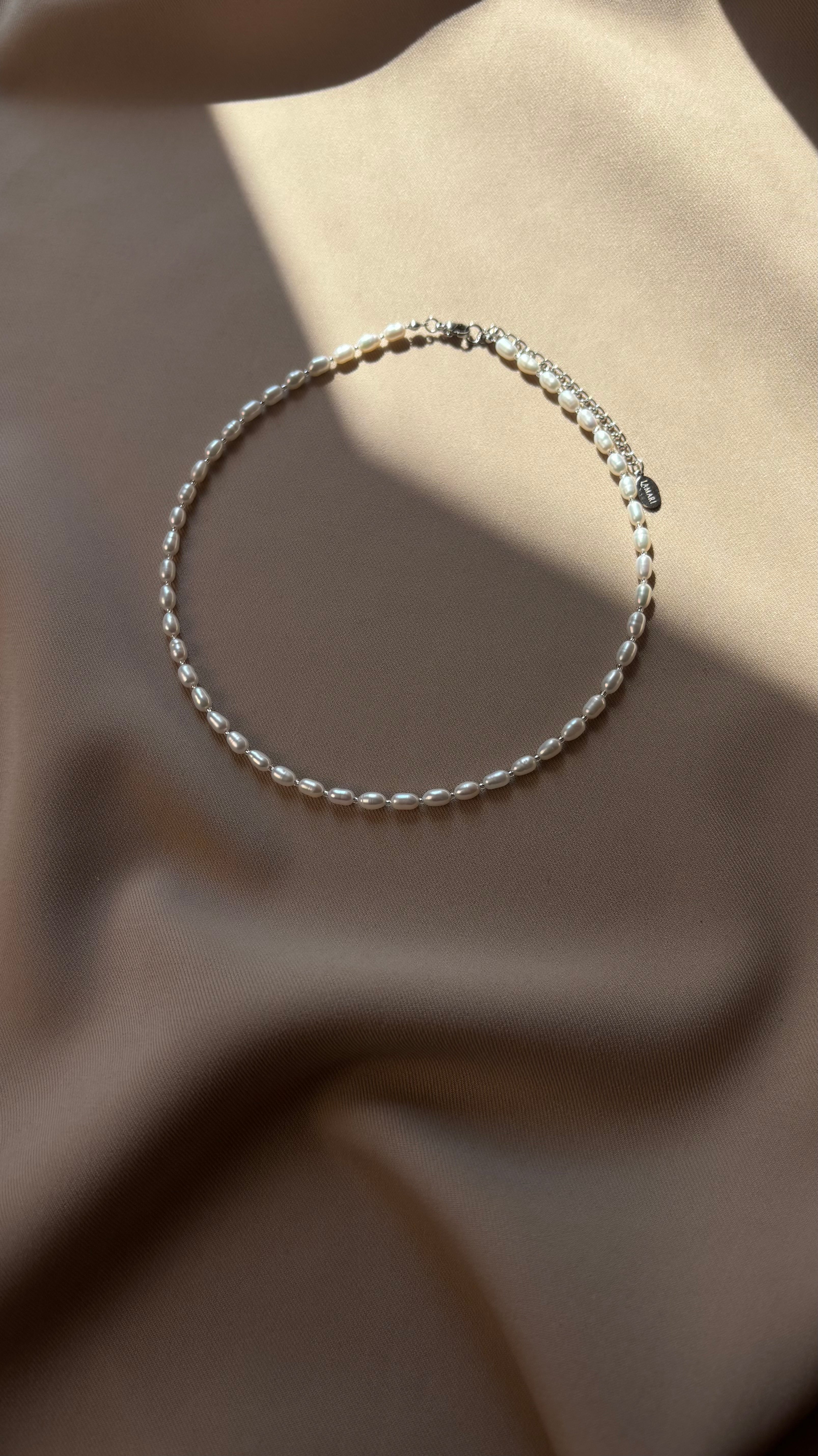 Silver-tone beaded bracelet on a beige fabric background