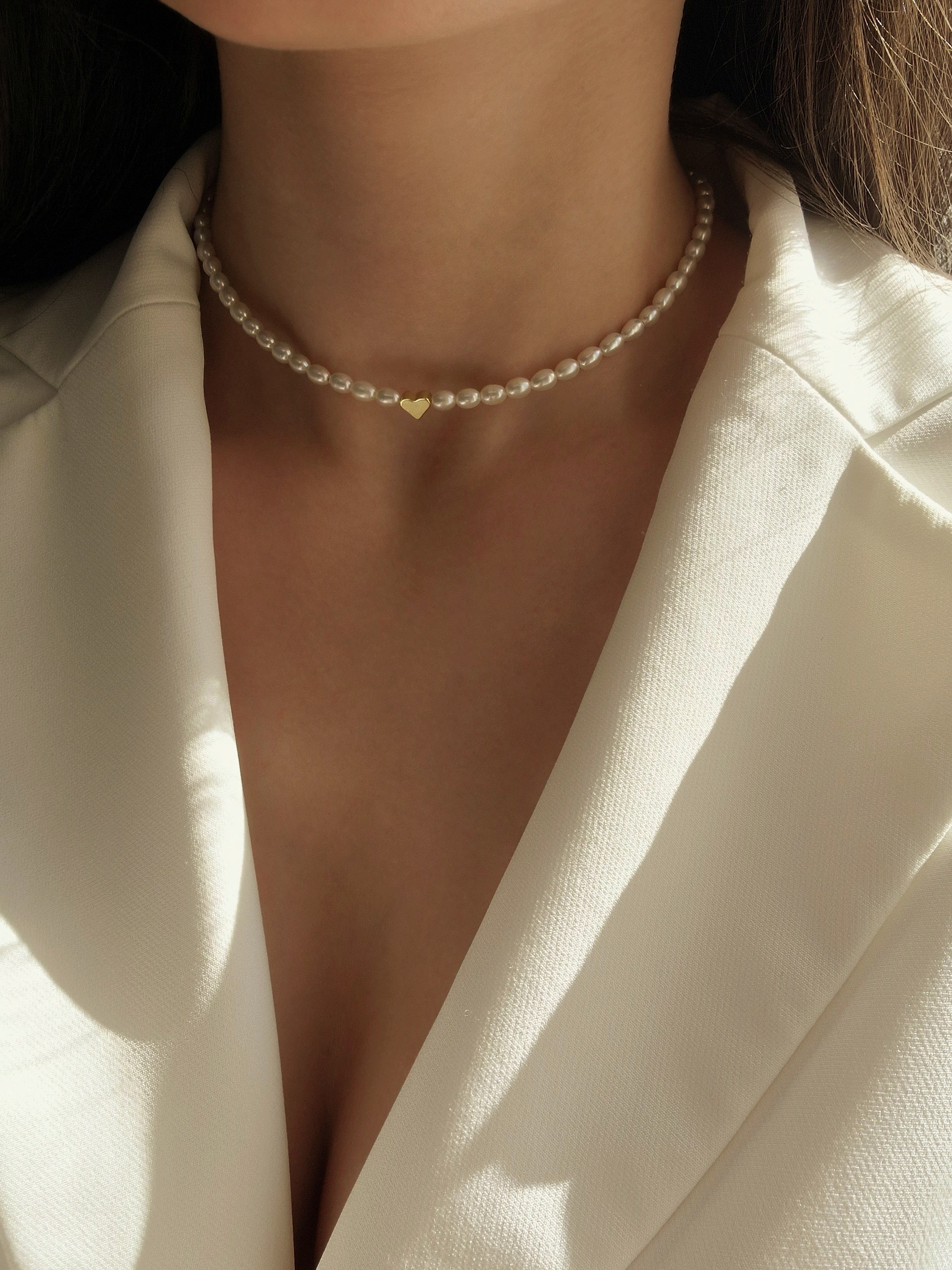 Natural pearl choker with radiant freshwater pearls and a dainty gold-tone heart charm, offering a minimalist and elegant look perfect for everyday wear or special occasions.