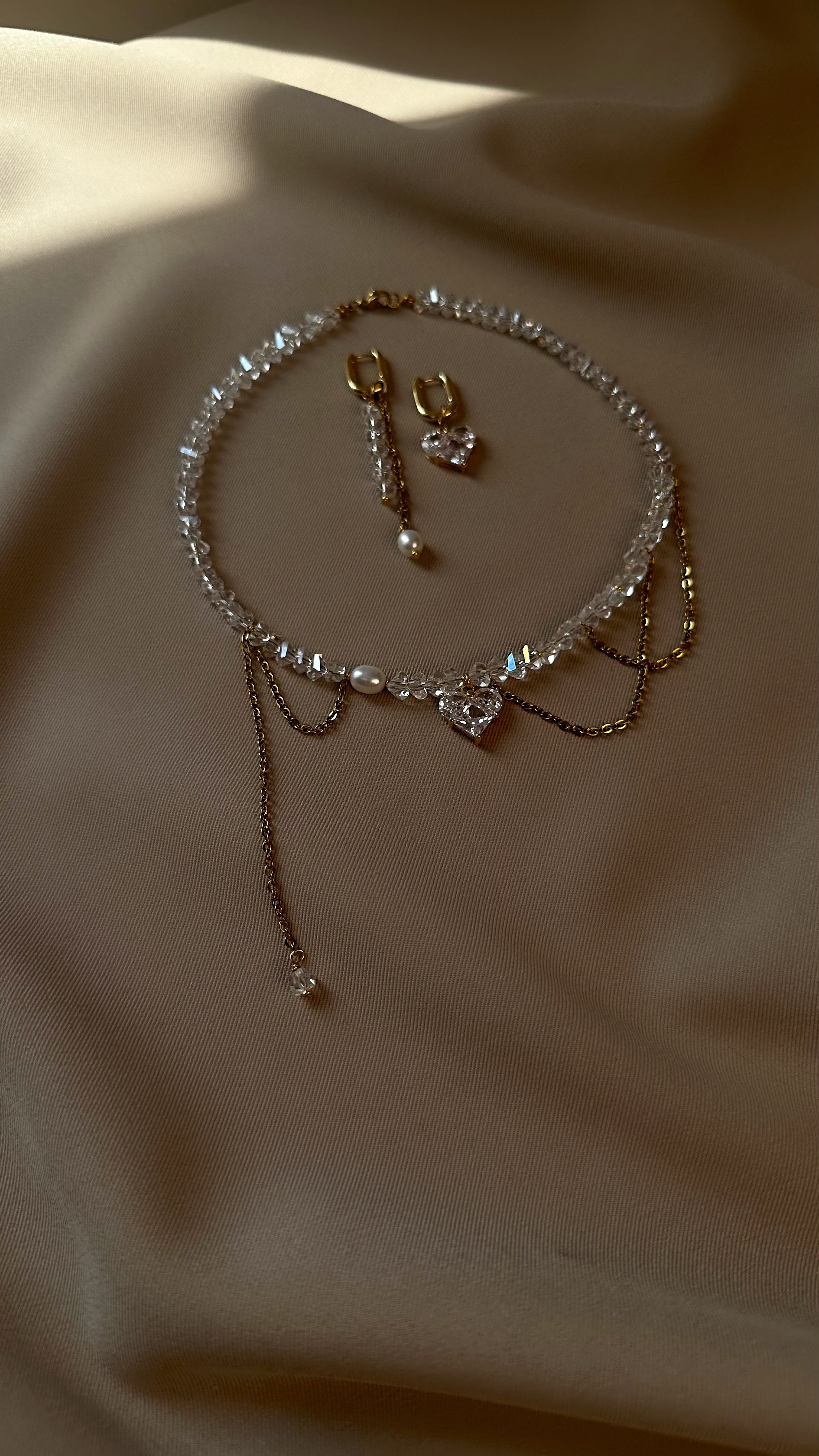 Set of jewelry necklace and earrings on a beige fabric background
