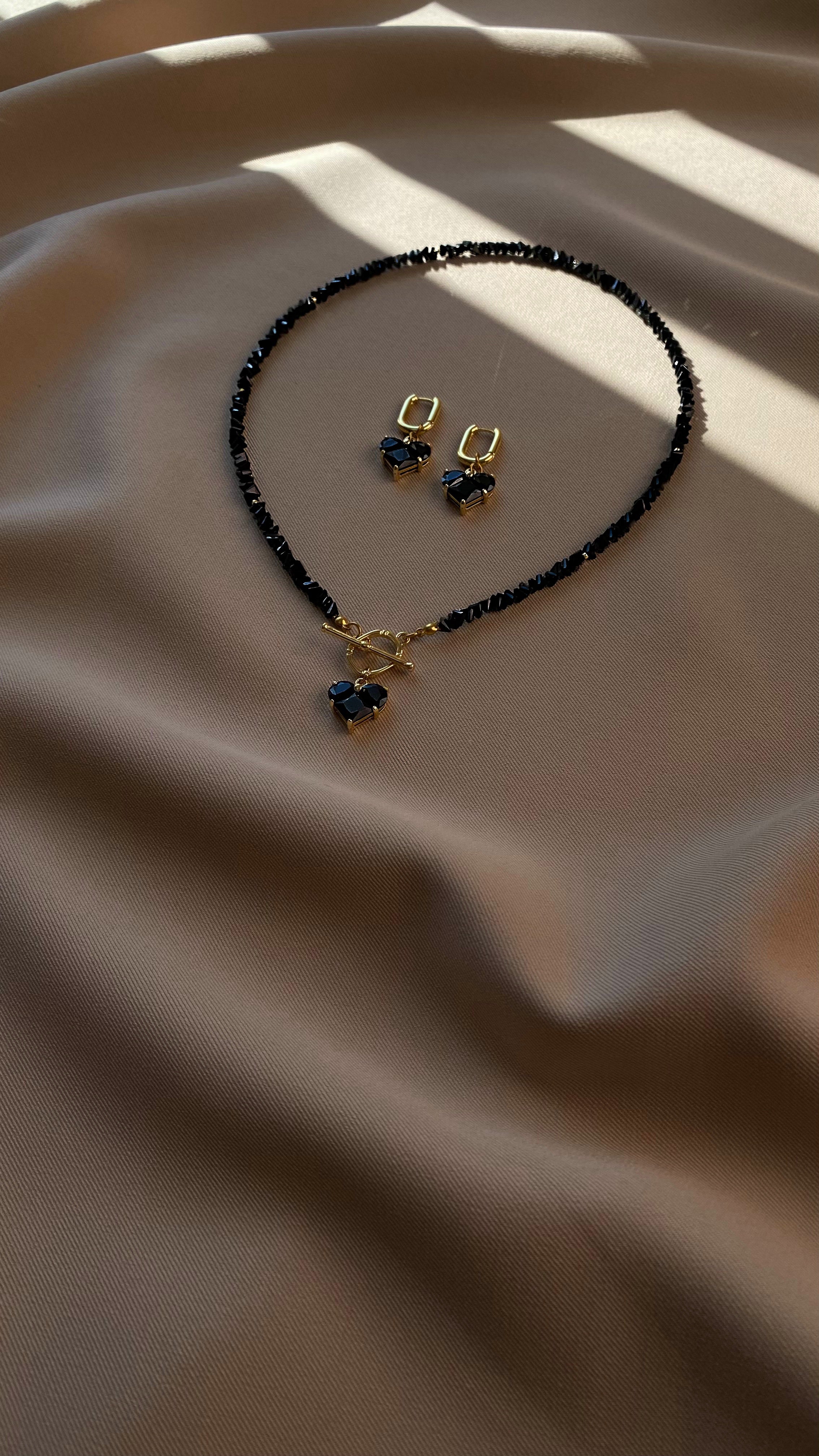 Woman wearing a black beaded necklace and earrings against a gray background