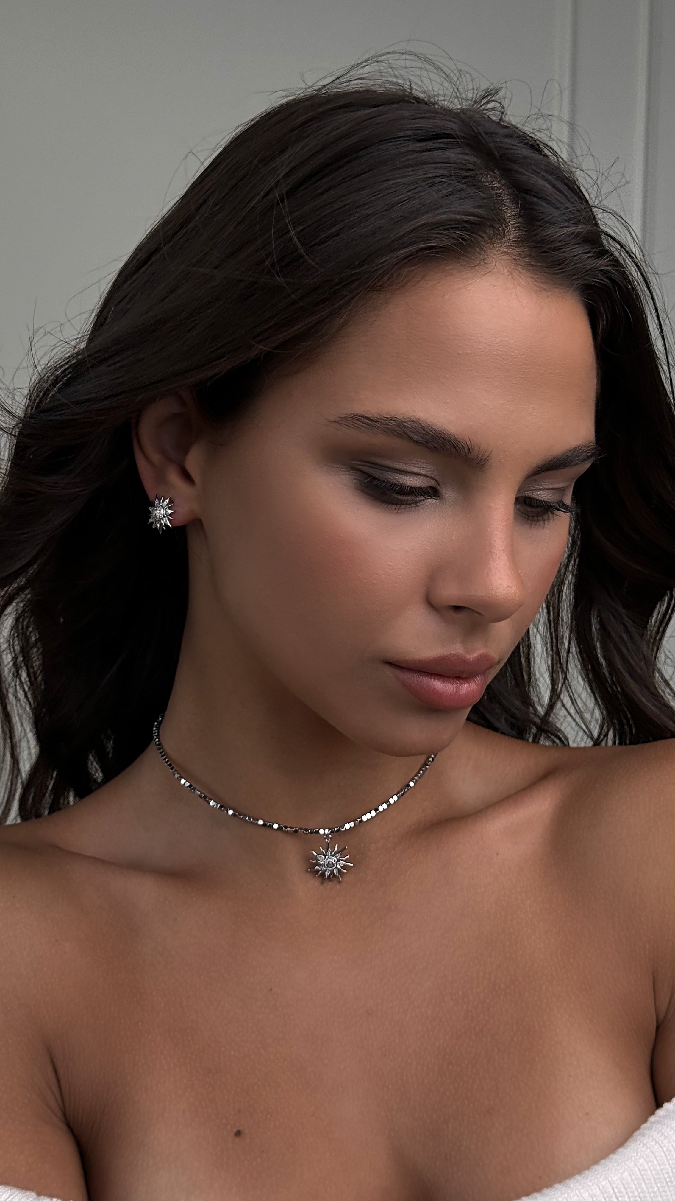 Woman wearing a necklace with a gray background