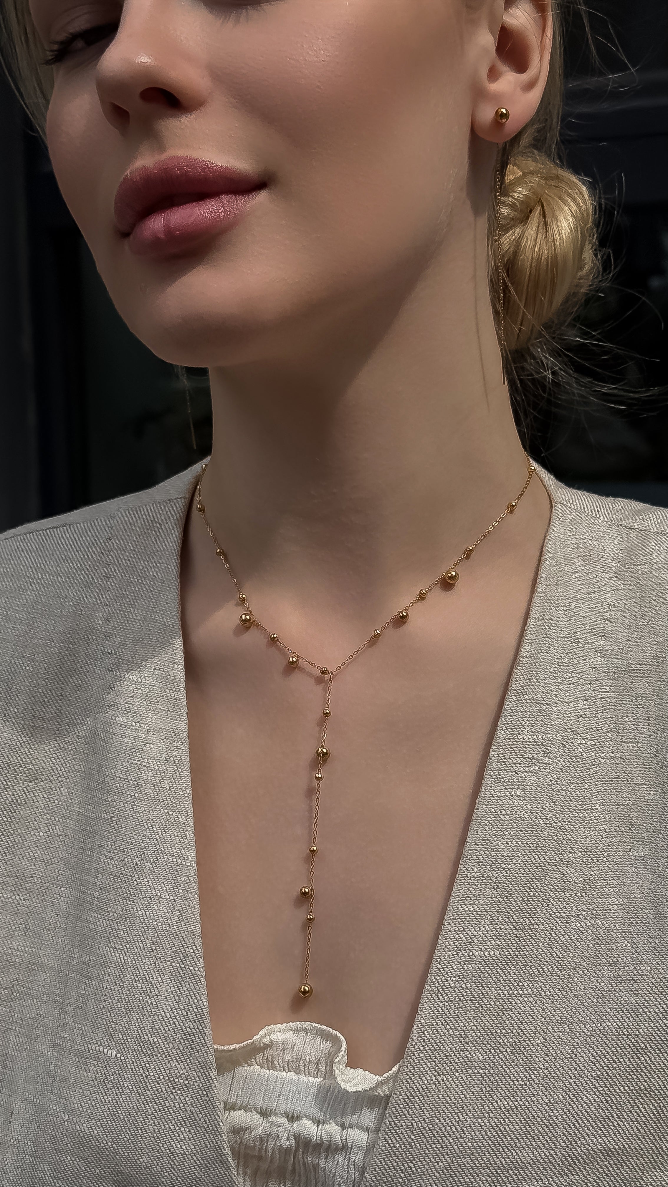 Bridal jewelry set featuring a gold-plated Y-shaped necklace with delicate ball drops and matching long dangle earrings, styled on a model in a minimalistic wedding look.