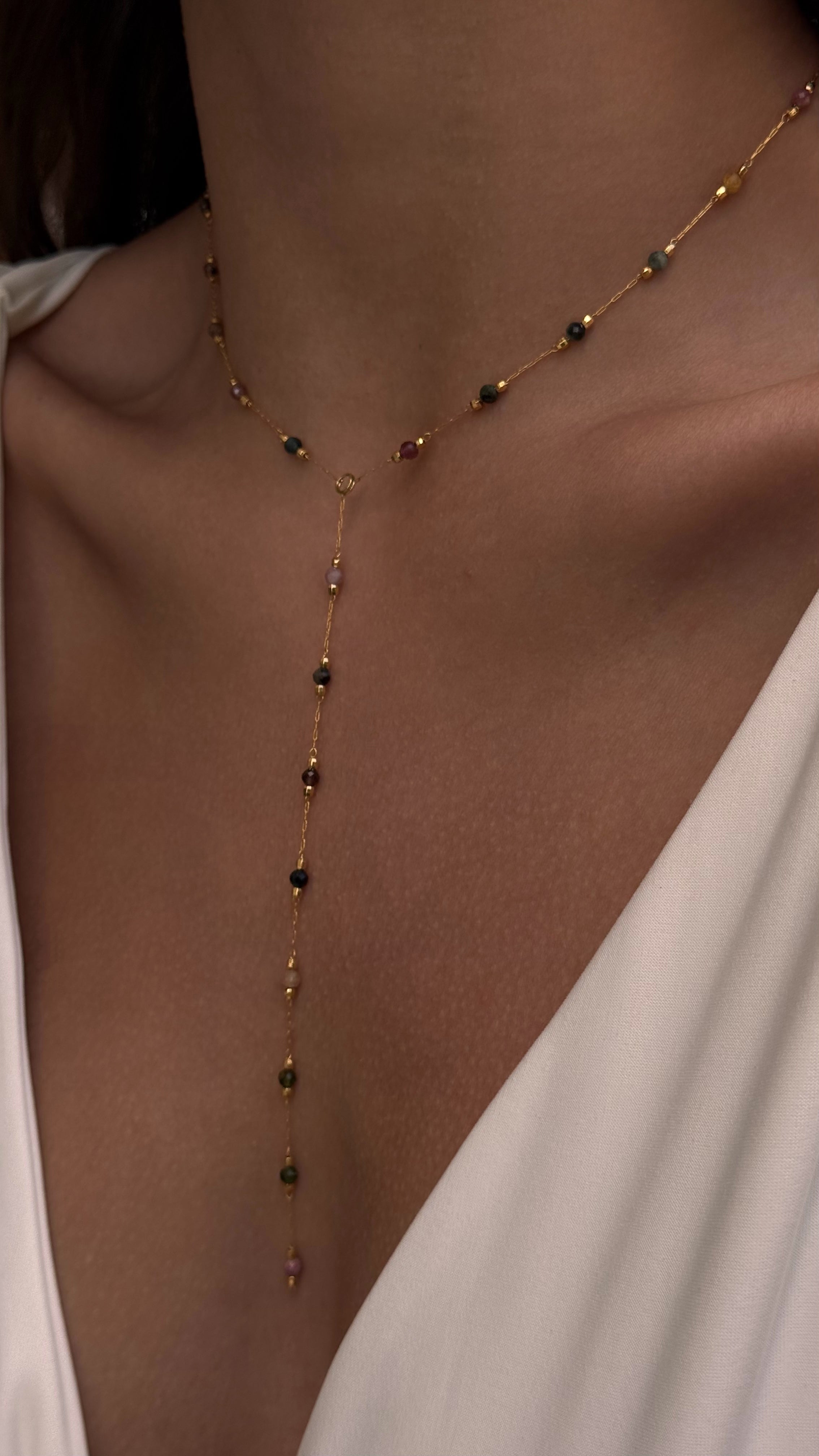 Necklace with small beads on a person wearing a white top