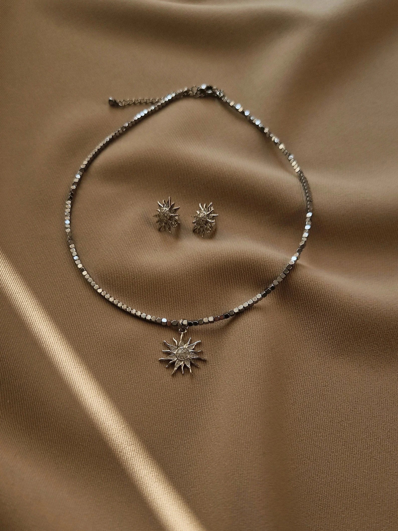 Necklace and earrings with sunflower designs on a beige fabric background