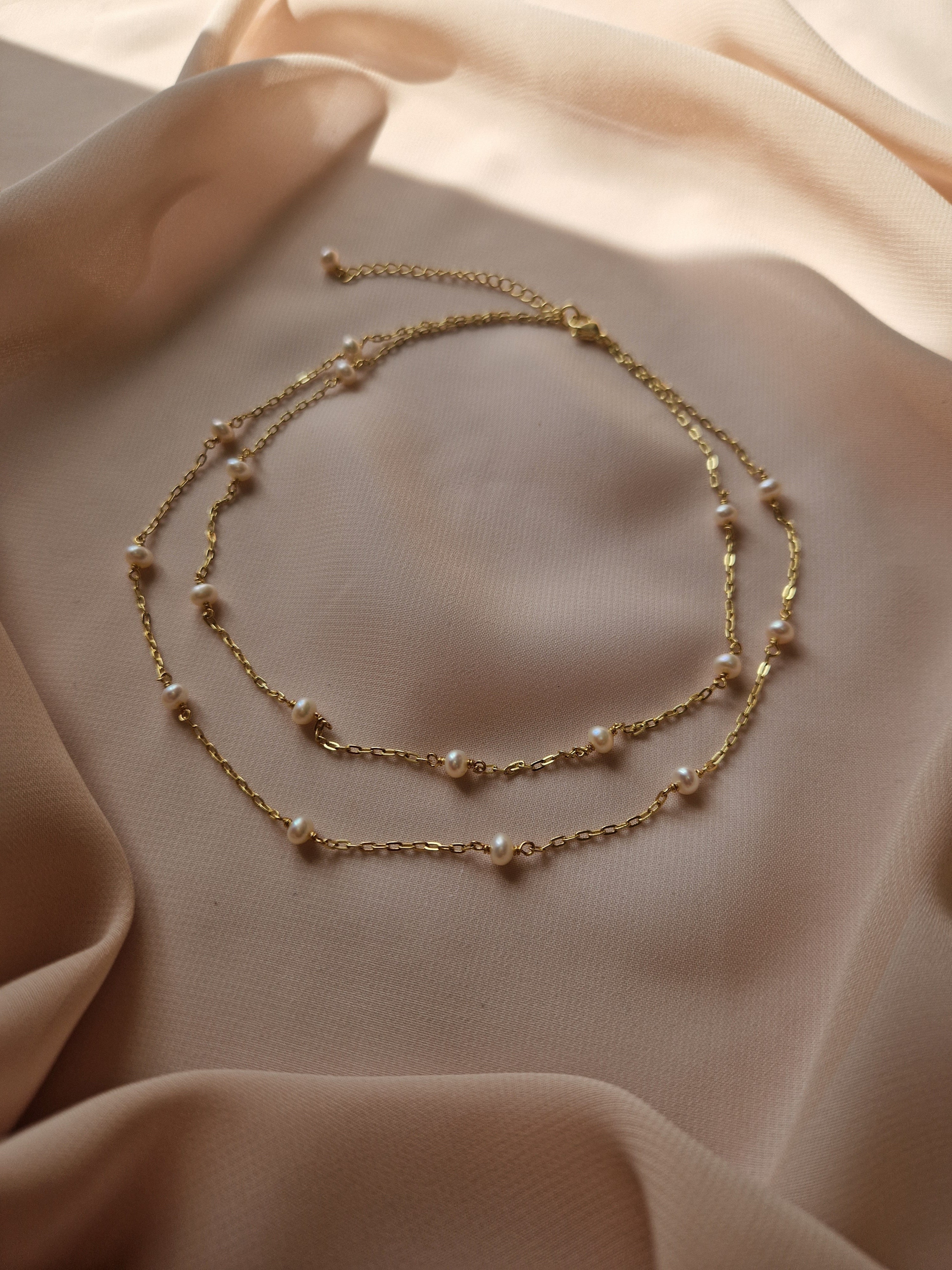 Delicate double-layered necklace featuring natural freshwater pearl accents, crafted from high-quality gold-plated brass for a warm and elegant feminine look.