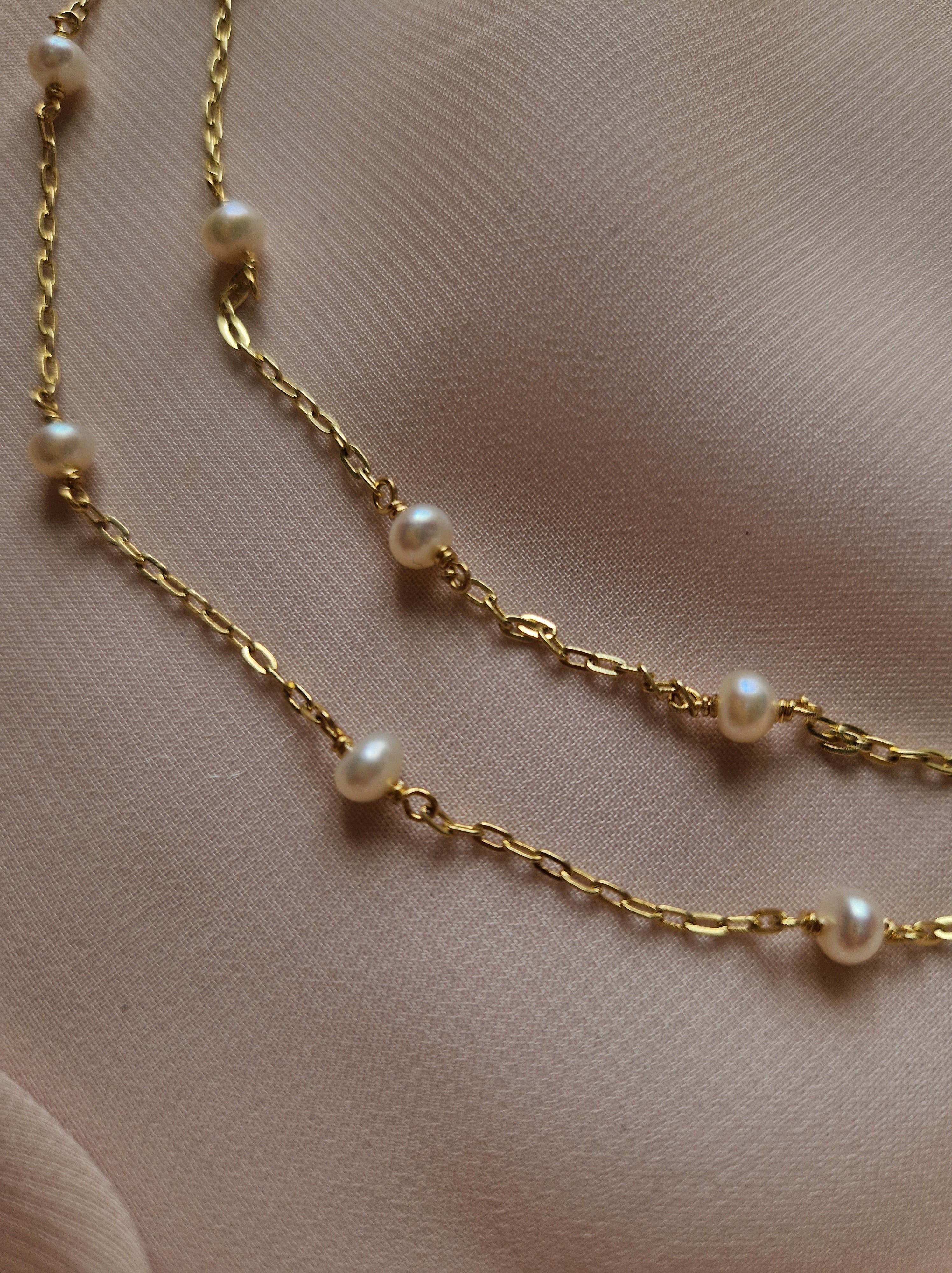 Delicate double-layered necklace featuring natural freshwater pearl accents, crafted from high-quality gold-plated brass for a warm and elegant feminine look.