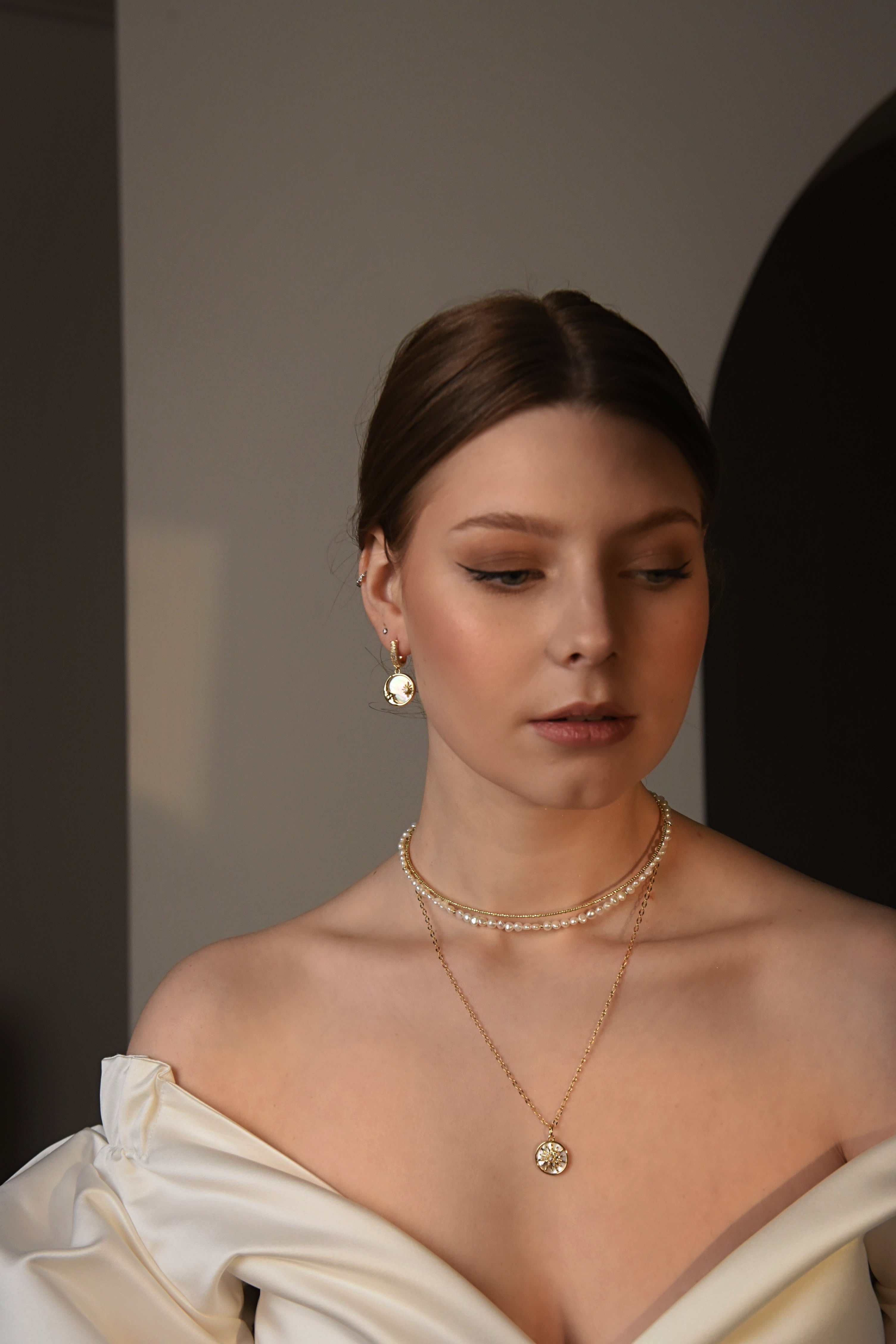 Woman wearing gold-plated jewelry against a neutral background