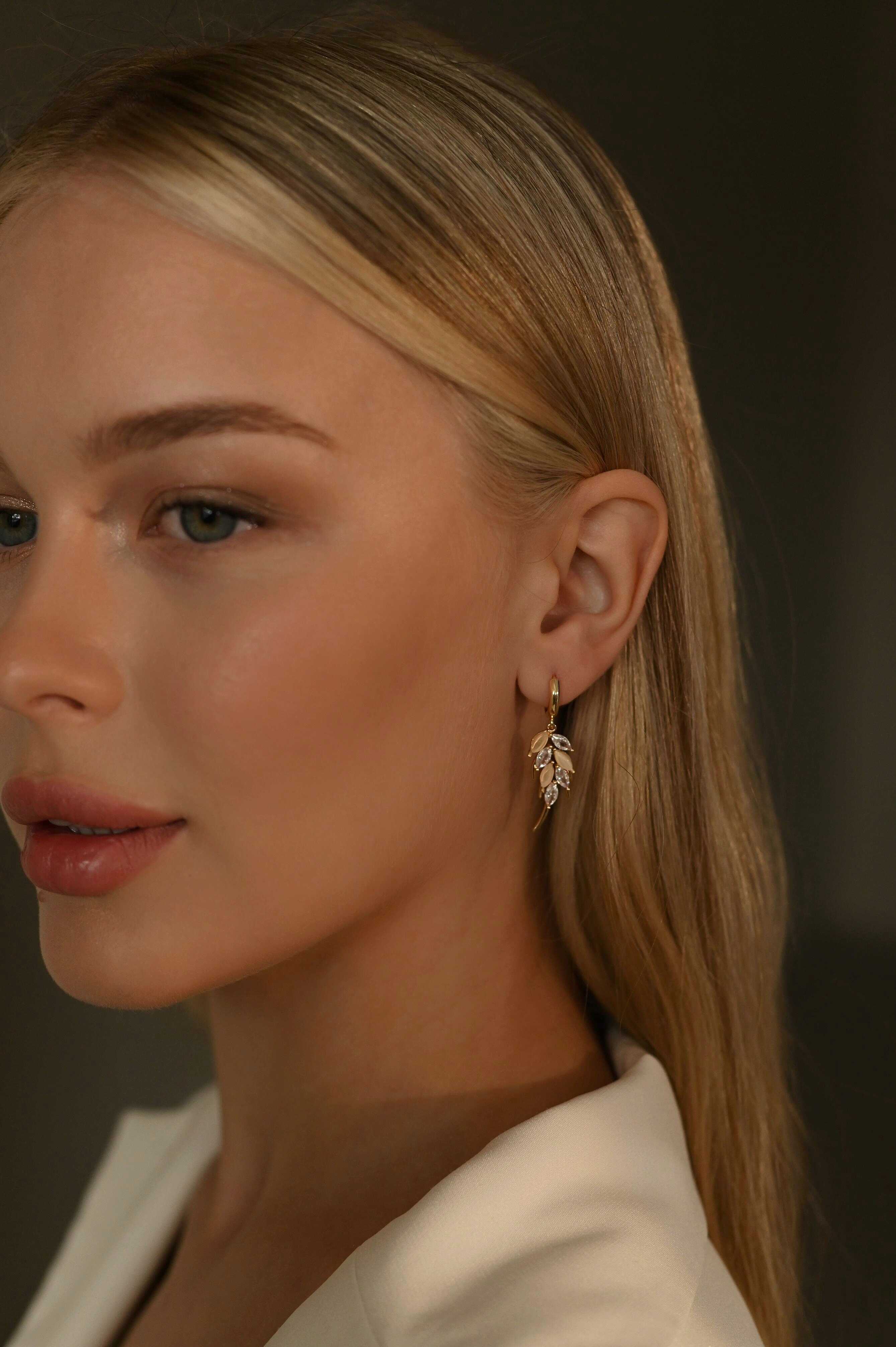 Close-up of a woman wearing a gold-plated earring with a dark background