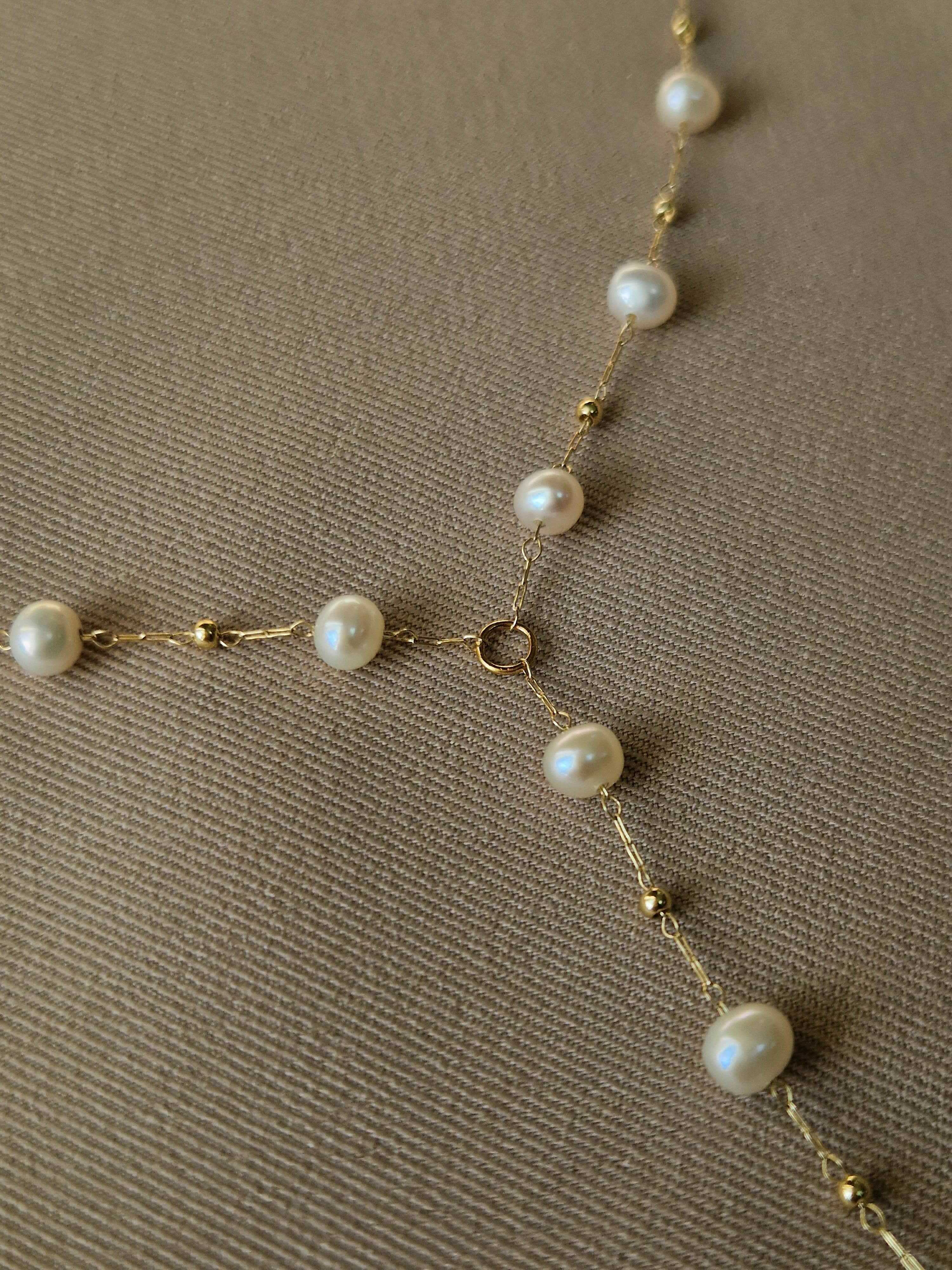 Pearl necklace with gold-plated chain on a brown background