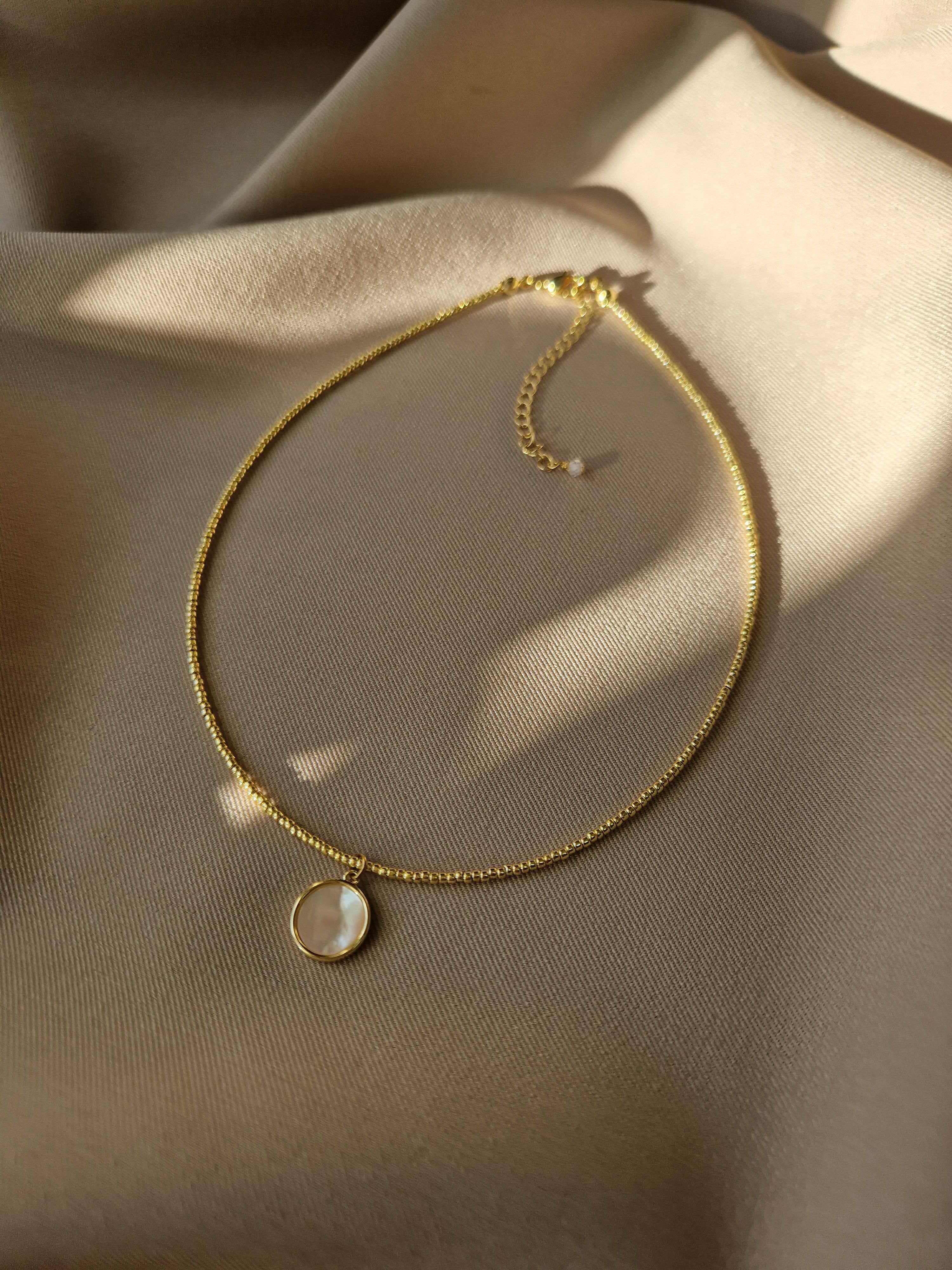 Delicate choker made from Japanese golden seed beads with a genuine mother-of-pearl pendant, offering a subtle and radiant look for everyday or special occasions.