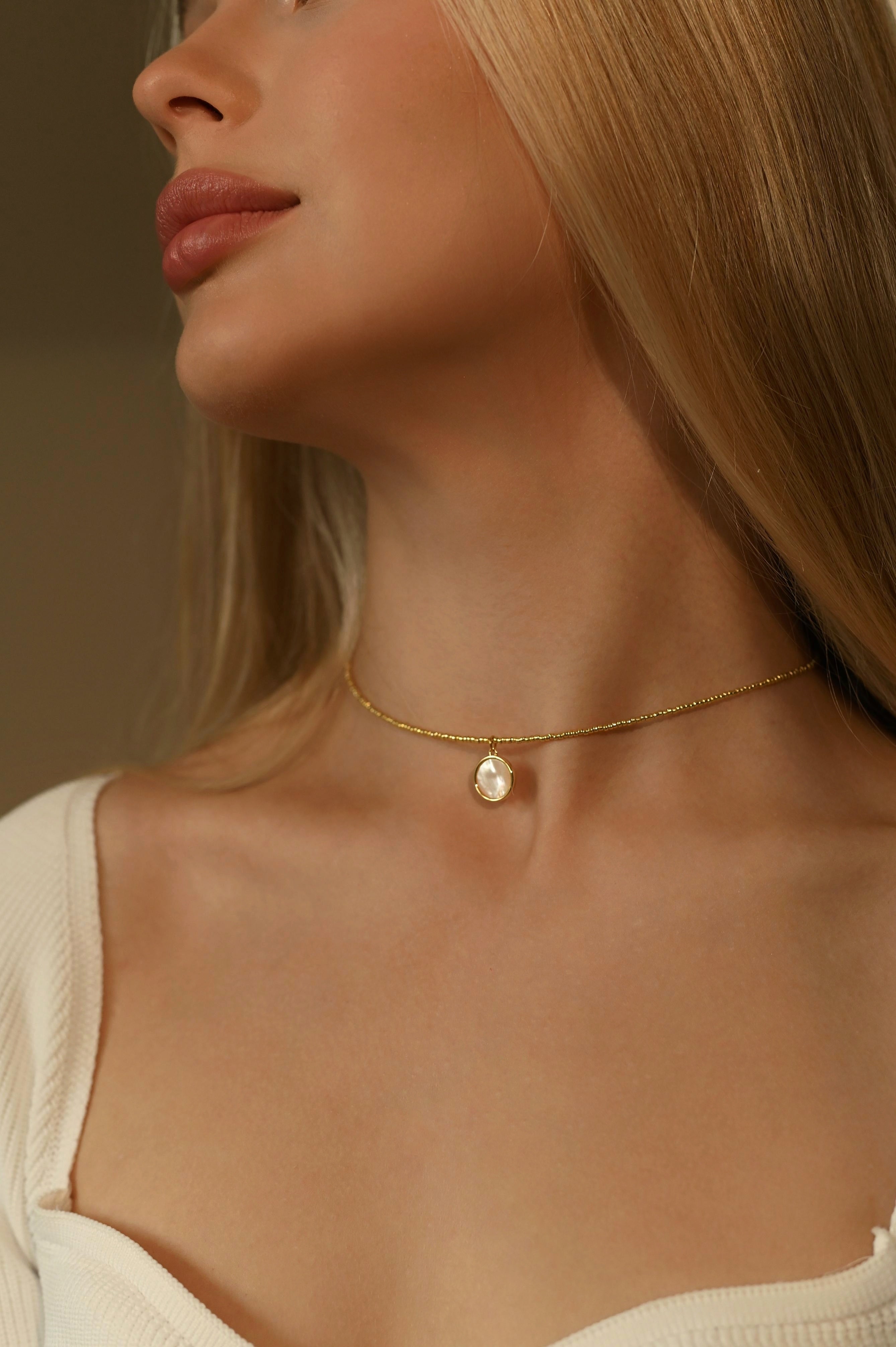 Delicate choker made of gold-tone Japanese seed beads with a natural mother-of-pearl pendant. Beads with durable galvanic coating. Premium gold-tone stainless steel hardware. Standard length 36 cm with a 6 cm extender.