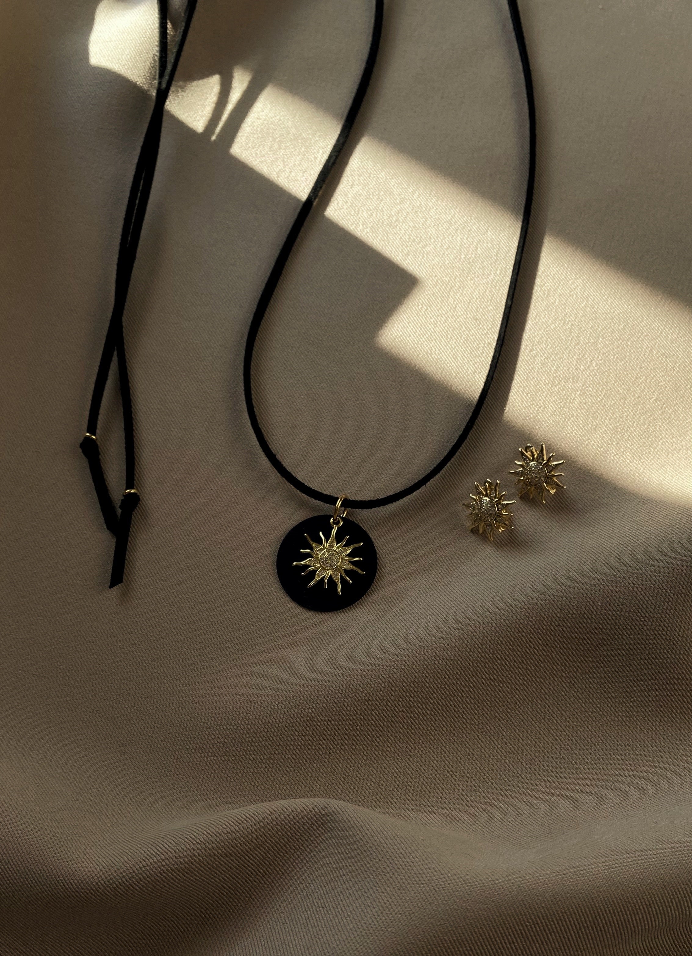 Bold black eco-suede cord necklace with removable cubic zirconia pendant, 150 cm versatile length, plus delicate sun-shaped earrings — stylish set for everyday and special occasions.