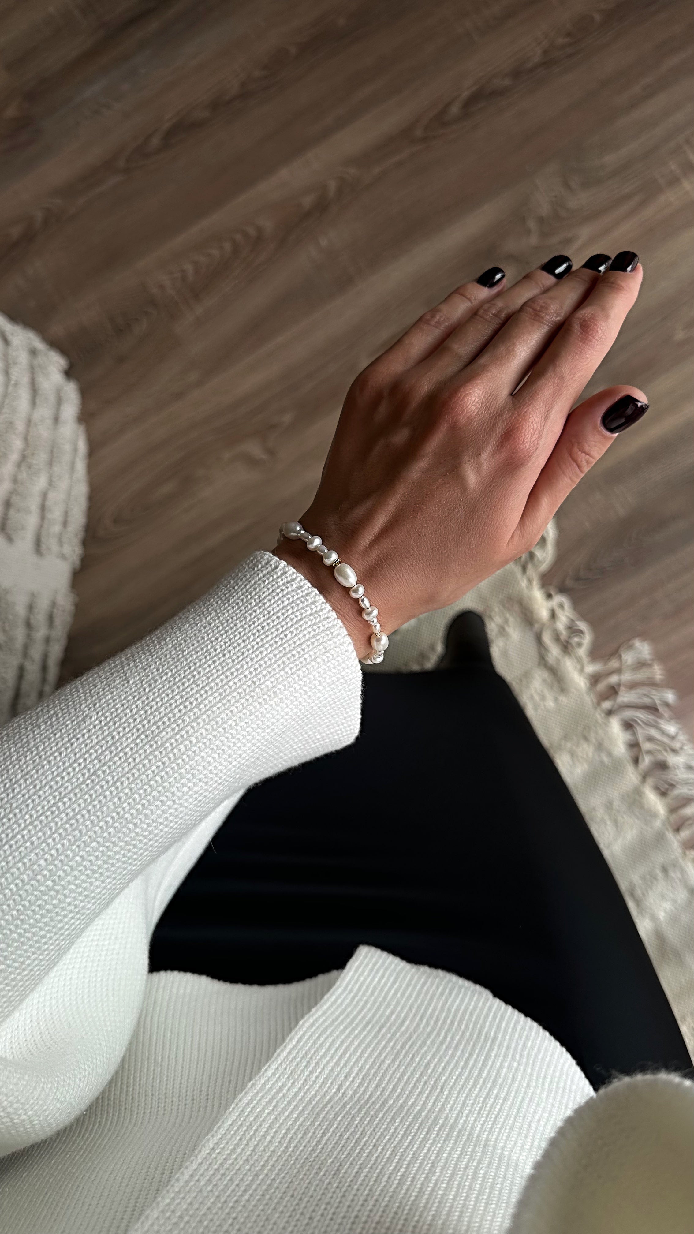Close-up of a person's hand wearing a bracelet on a wooden surface