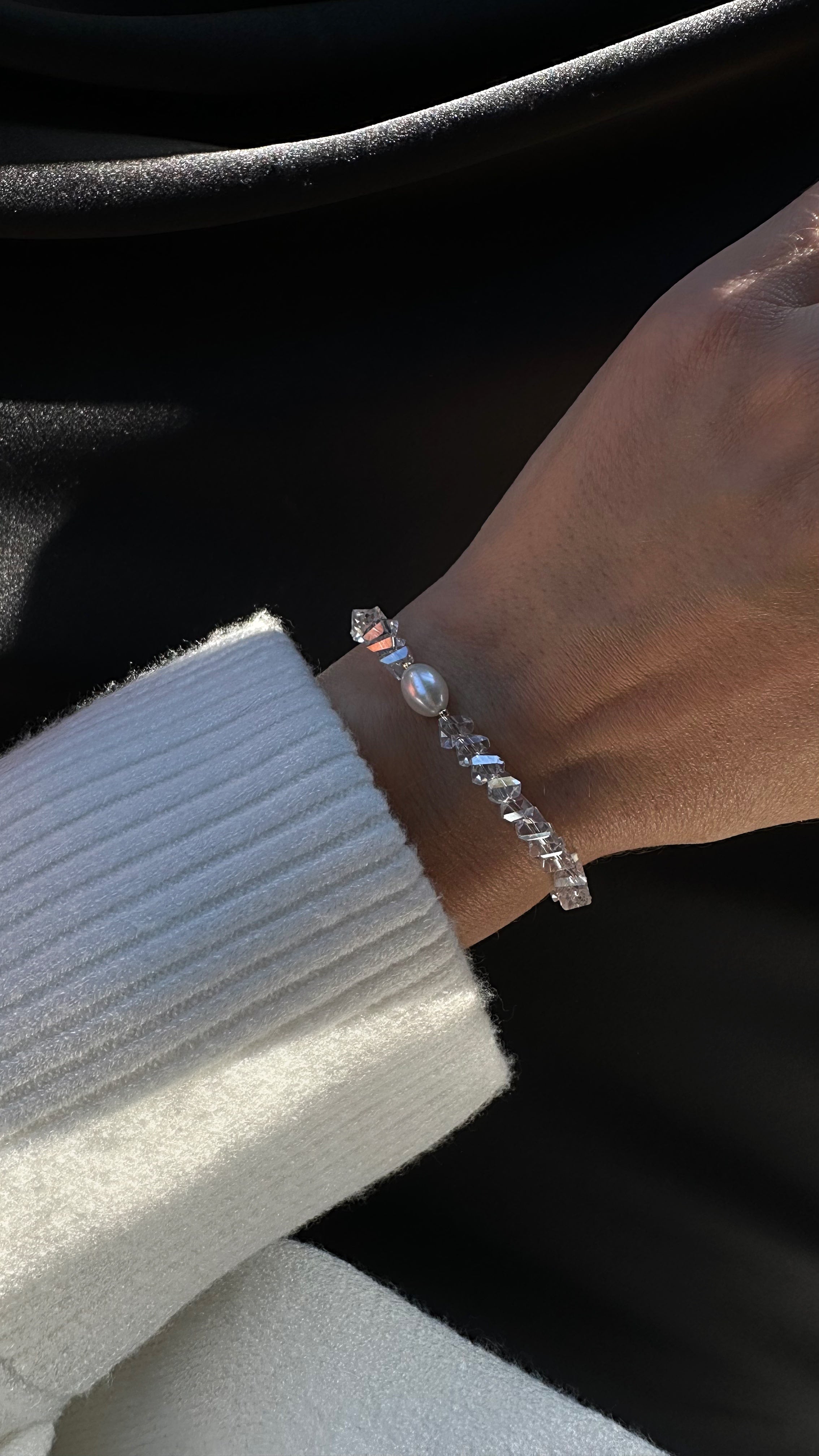 Close-up of a hand wearing a bracelet with a dark background