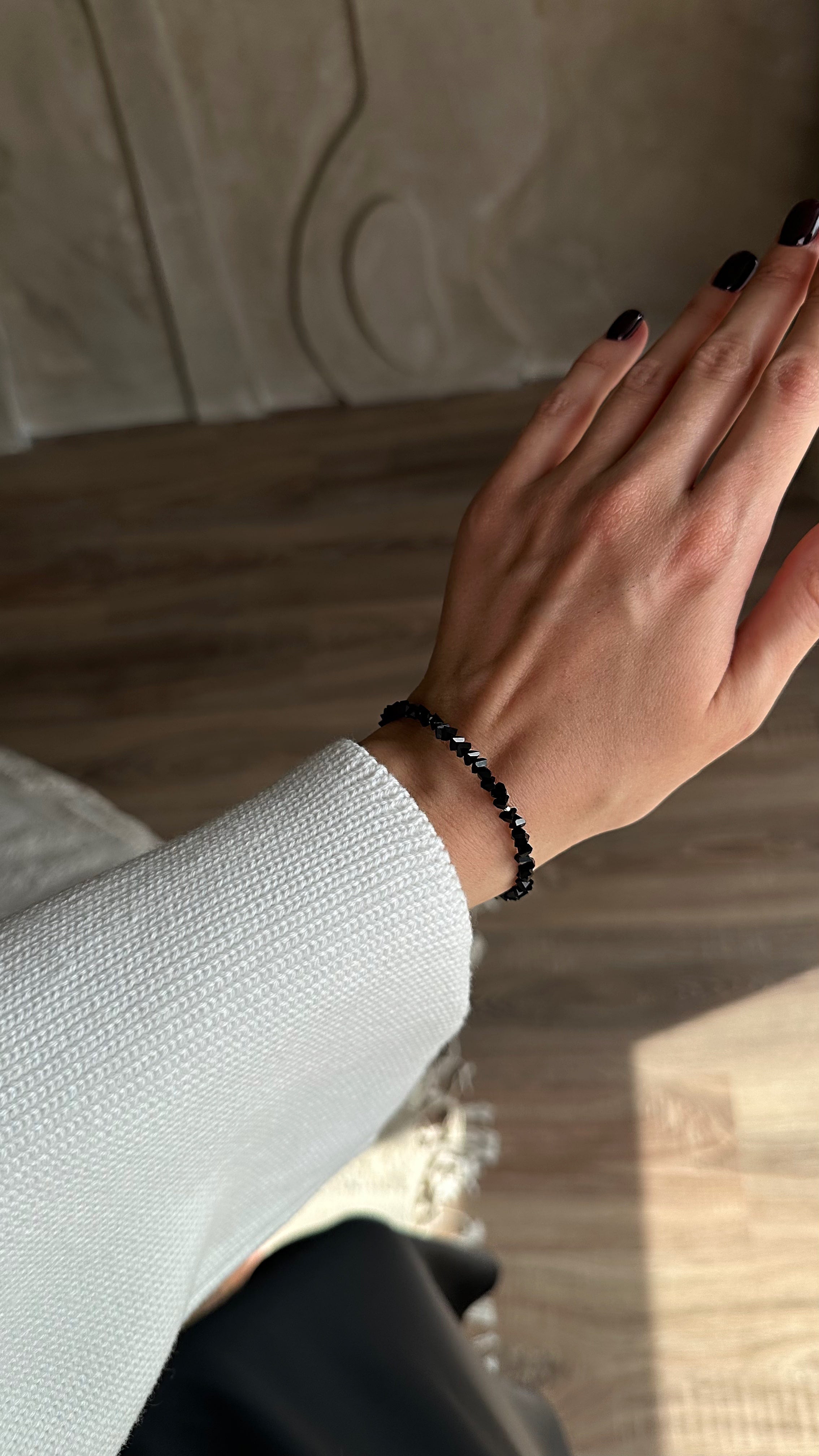 Hand wearing a black bracelet on a neutral background