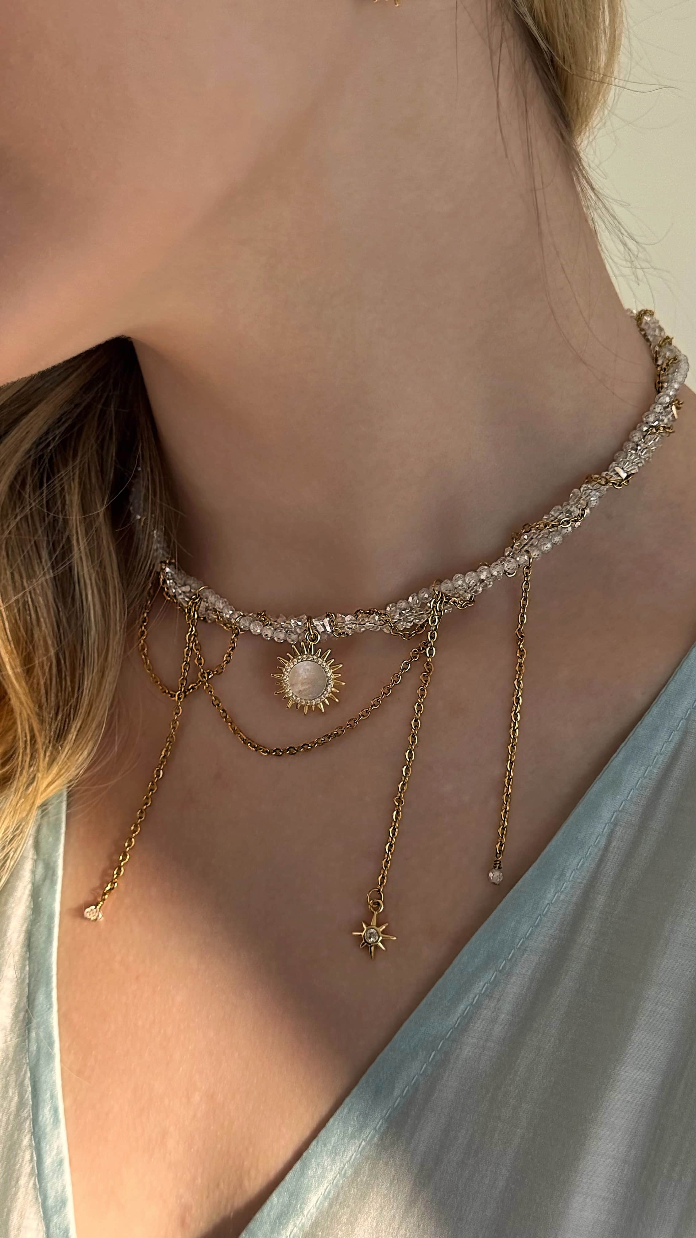 Gold plated sun pendant necklace with twisted chain and matching mother of pearl sunshine earrings displayed on a soft neutral background