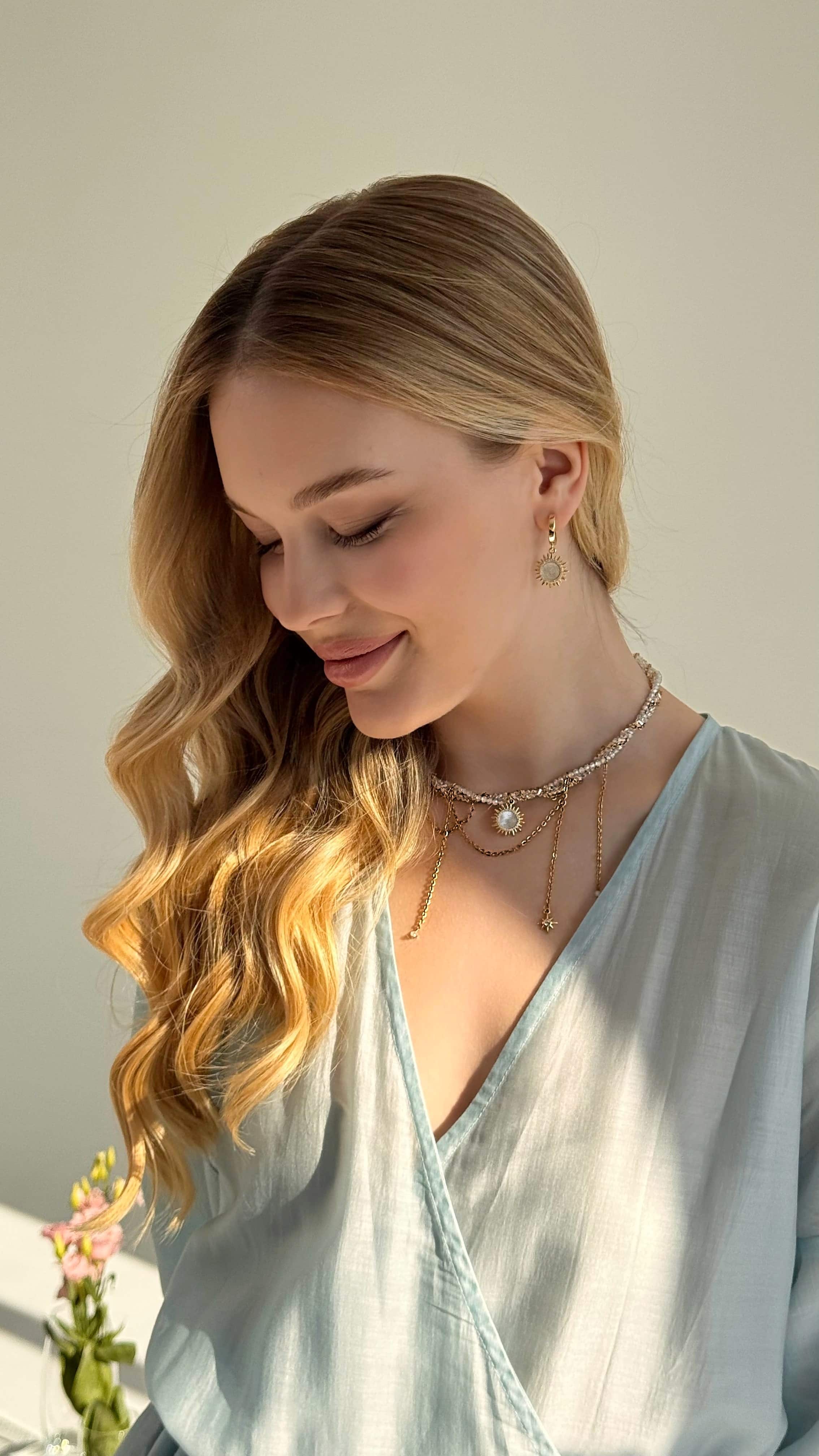 Gold plated sun pendant necklace with twisted chain and matching mother of pearl sunshine earrings displayed on a soft neutral background