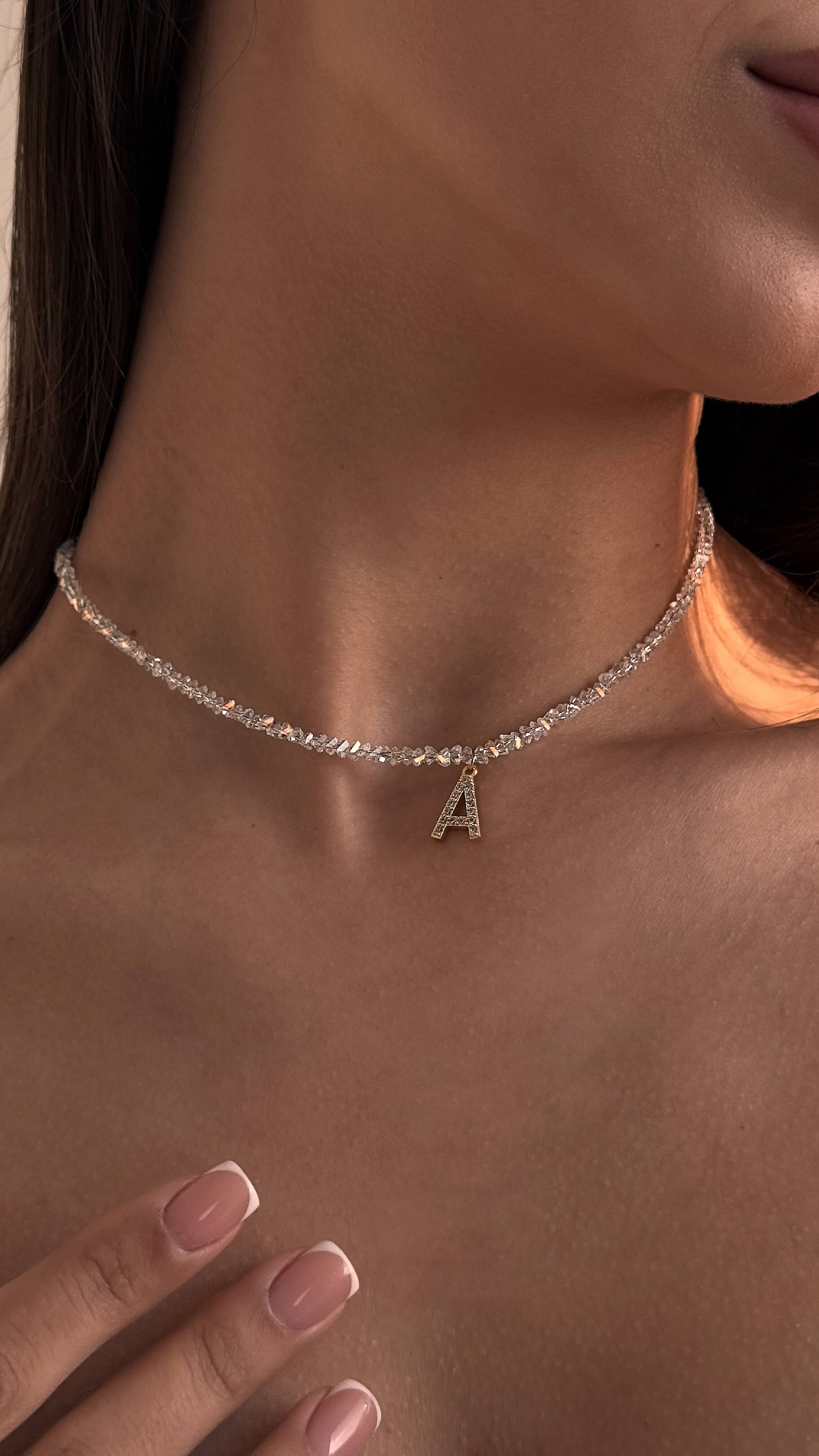 Necklace with a letter 'A' pendant worn by a person
