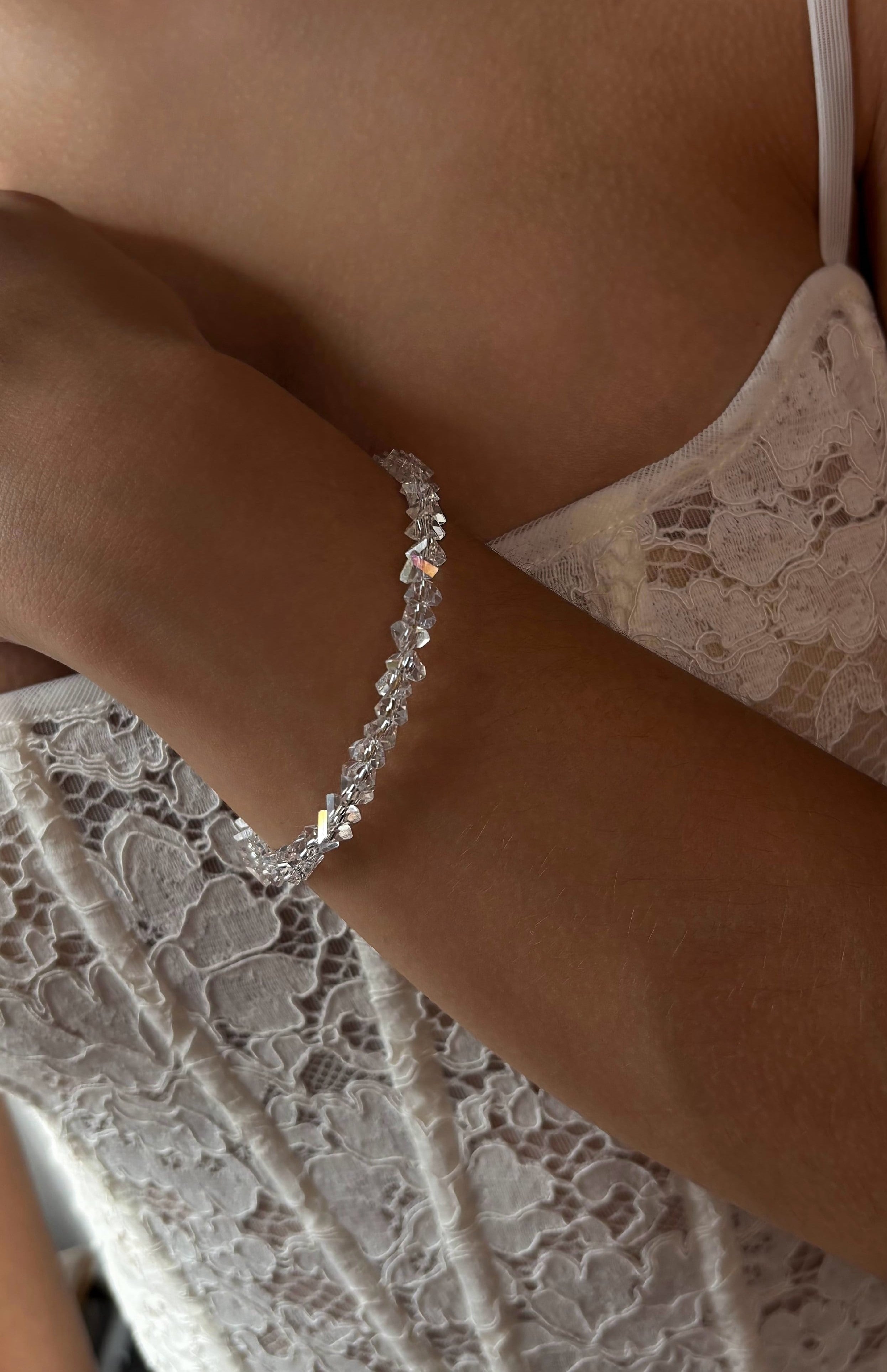 Silver bracelet on a wrist with a blurred lace garment in the background