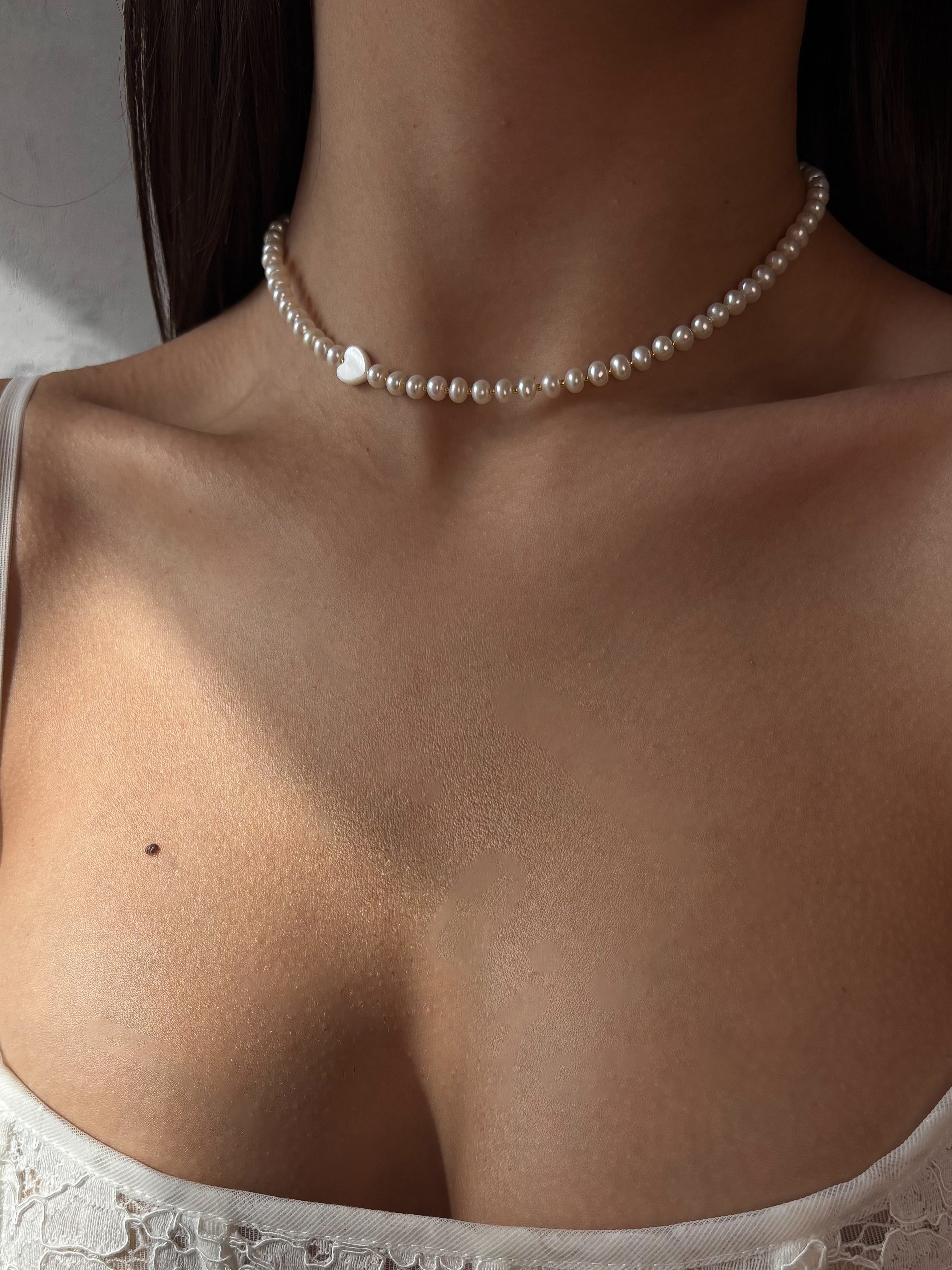 Pearl necklace worn by a person with a neutral background