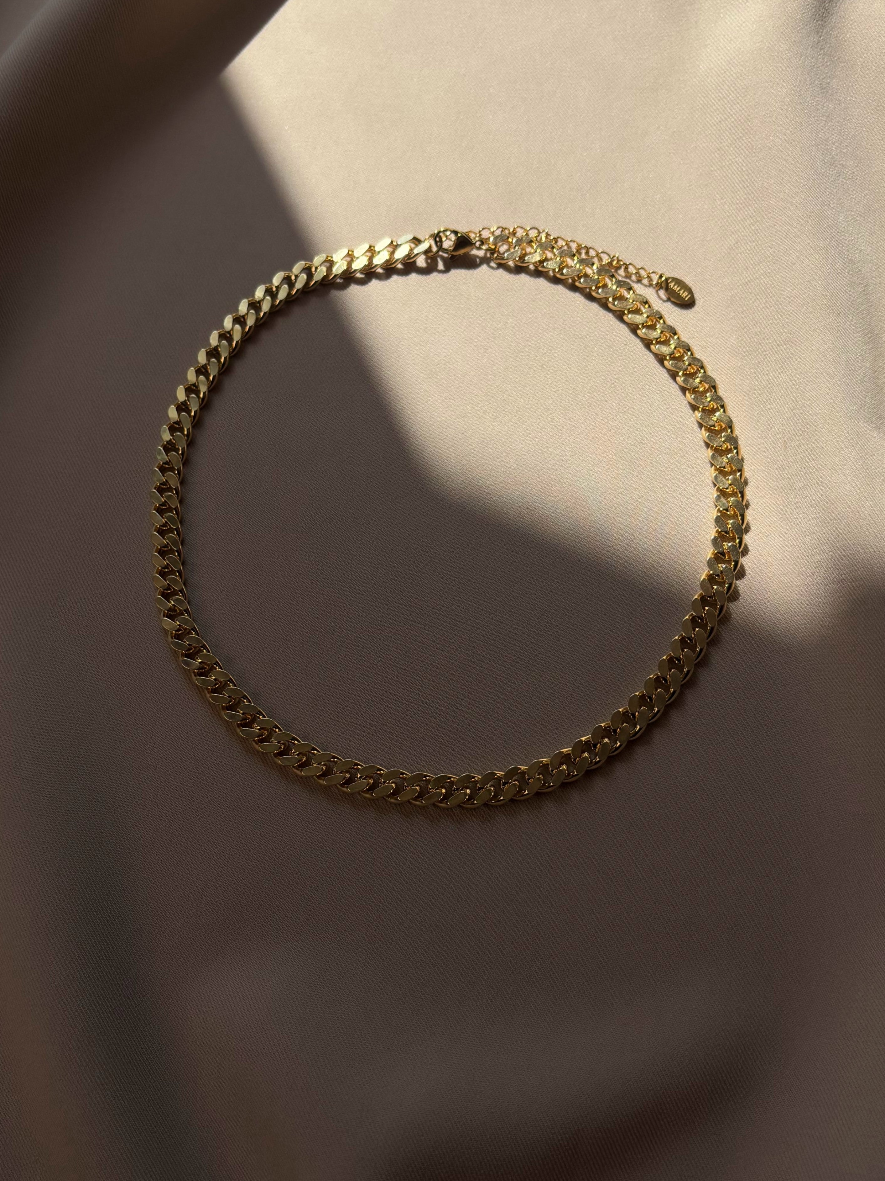 Gold-plated chain necklace on a beige fabric background