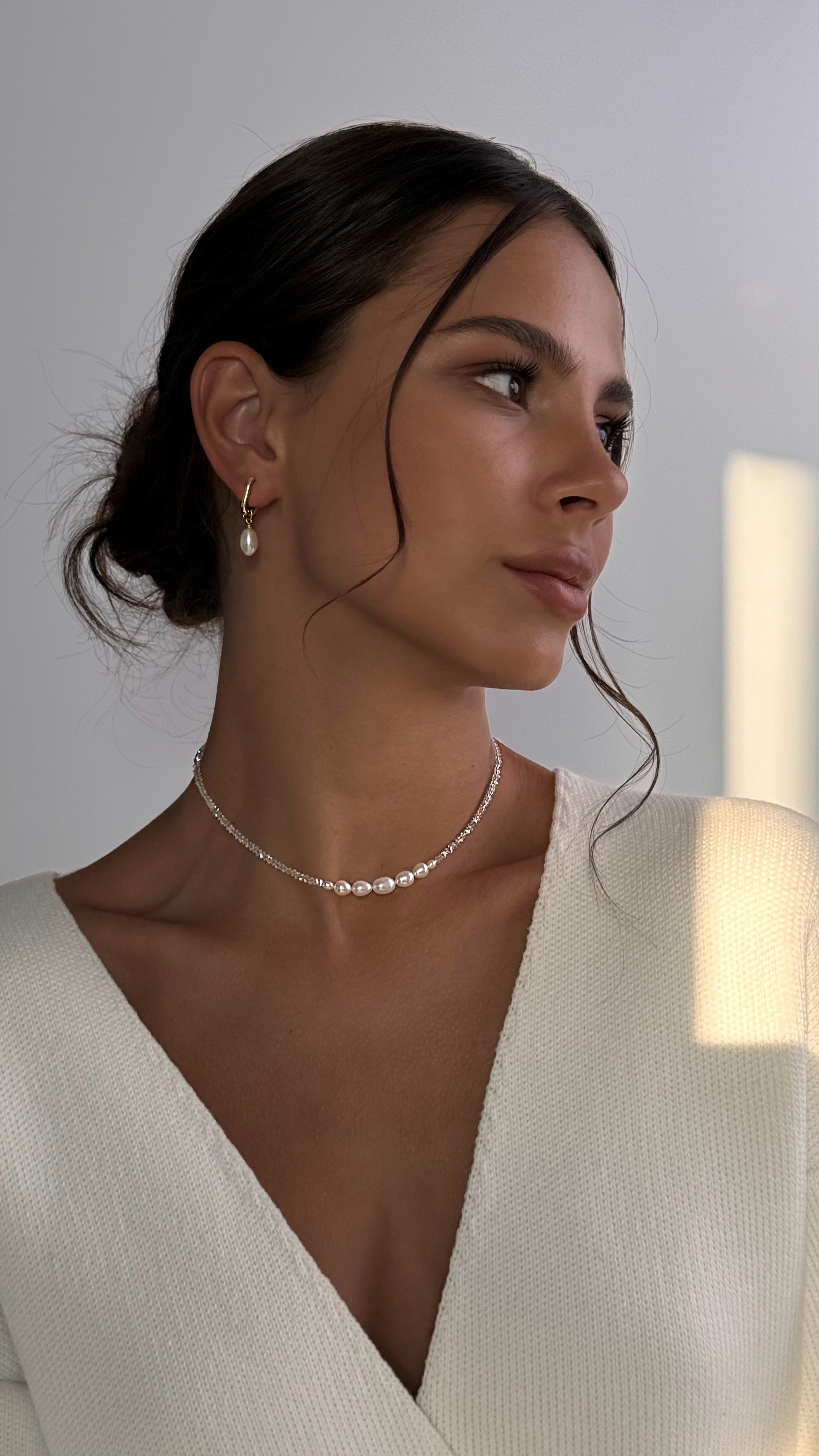 Woman wearing a pearl necklace against a neutral background