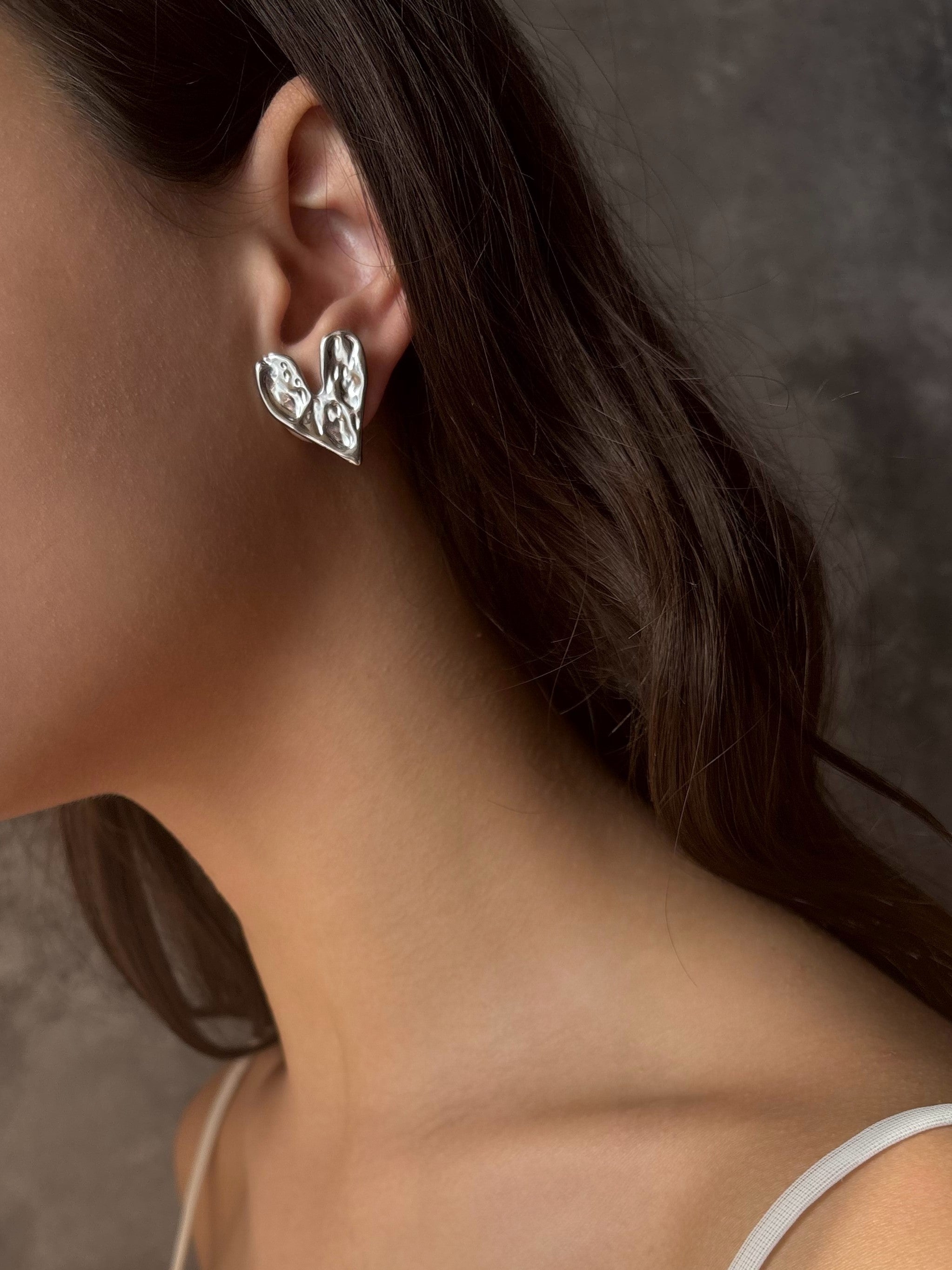 Close-up of a person wearing a silver earring with a dark background