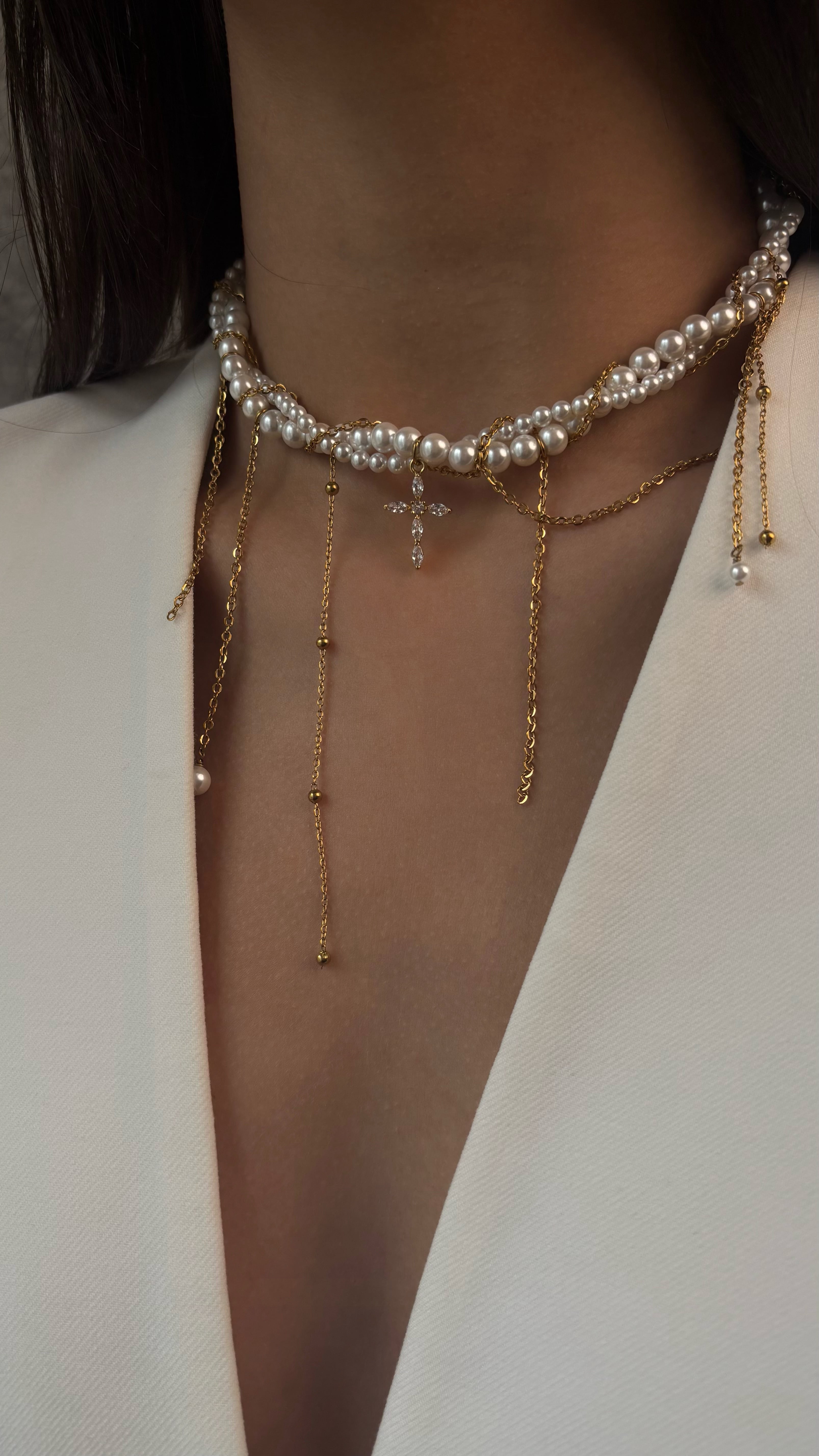 Close-up of a person wearing multiple necklaces with pearls and gold chains.