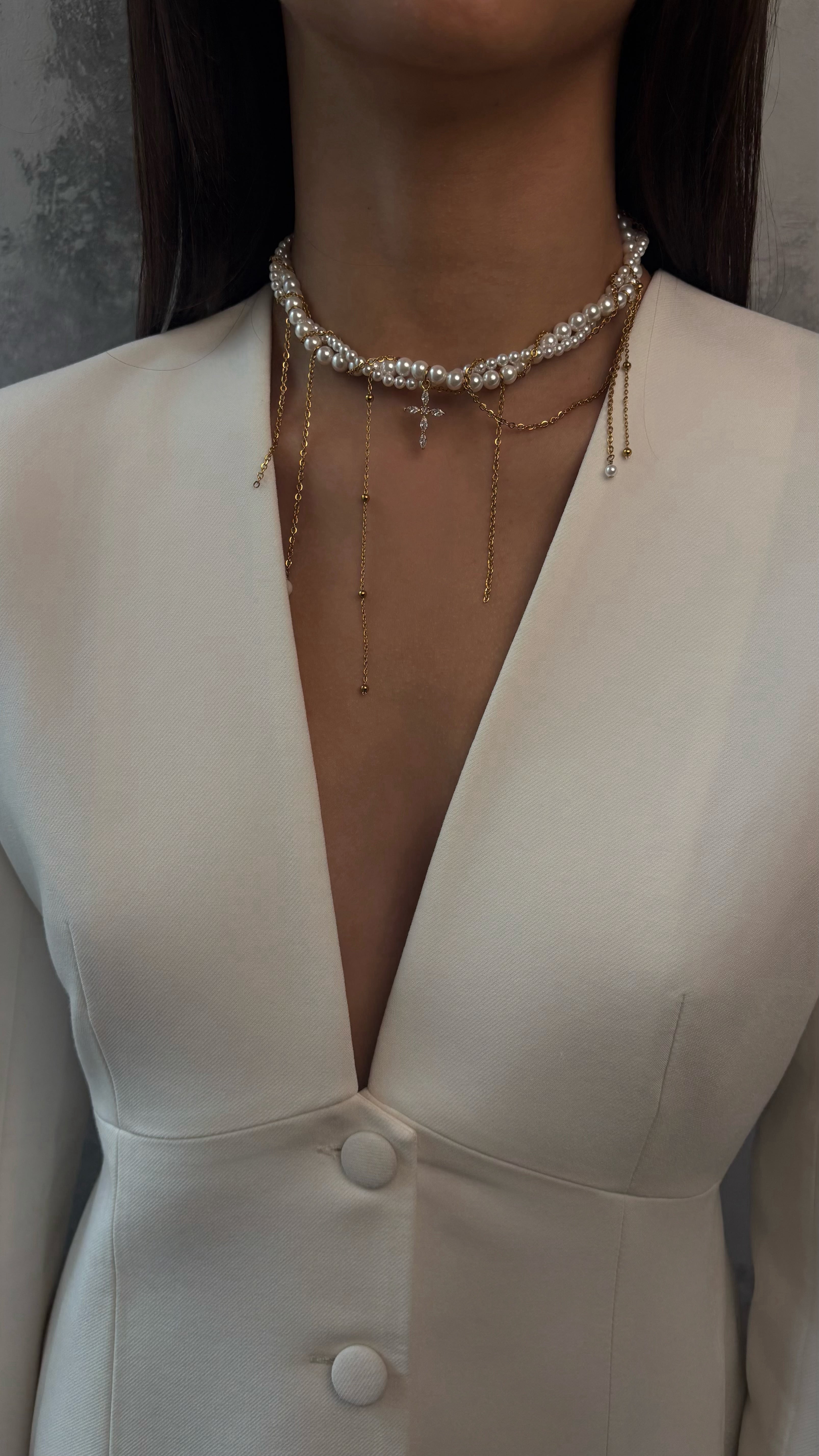 Close-up of a person wearing a pearl necklace with a plain background