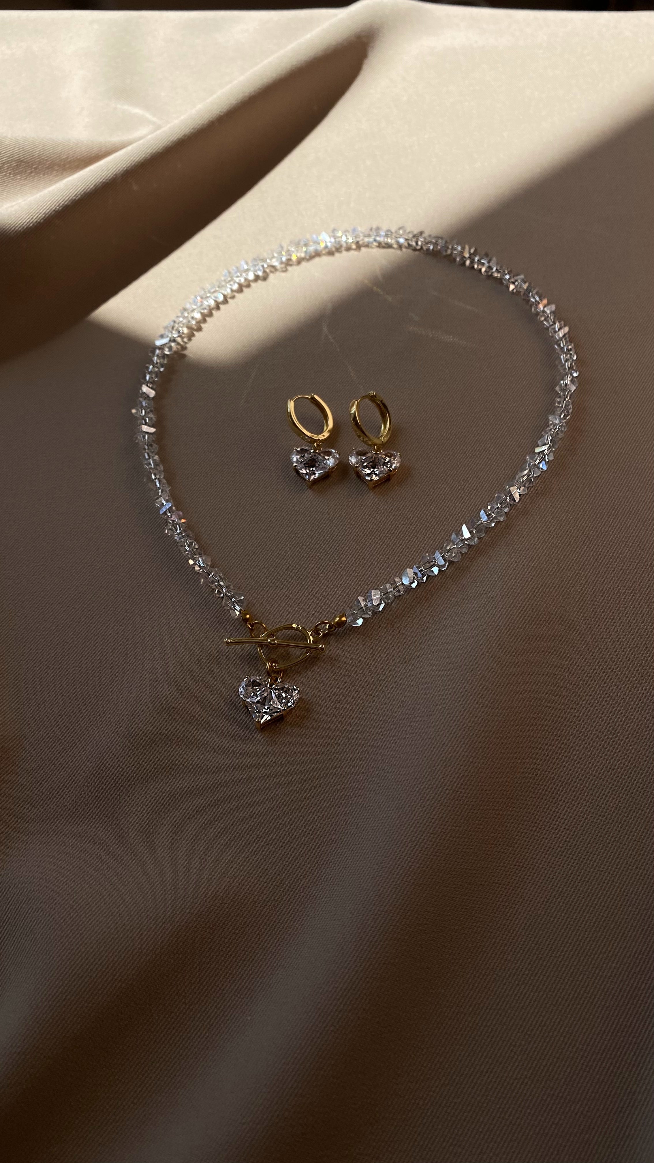 Jewelry set with necklace and earrings on a beige fabric background