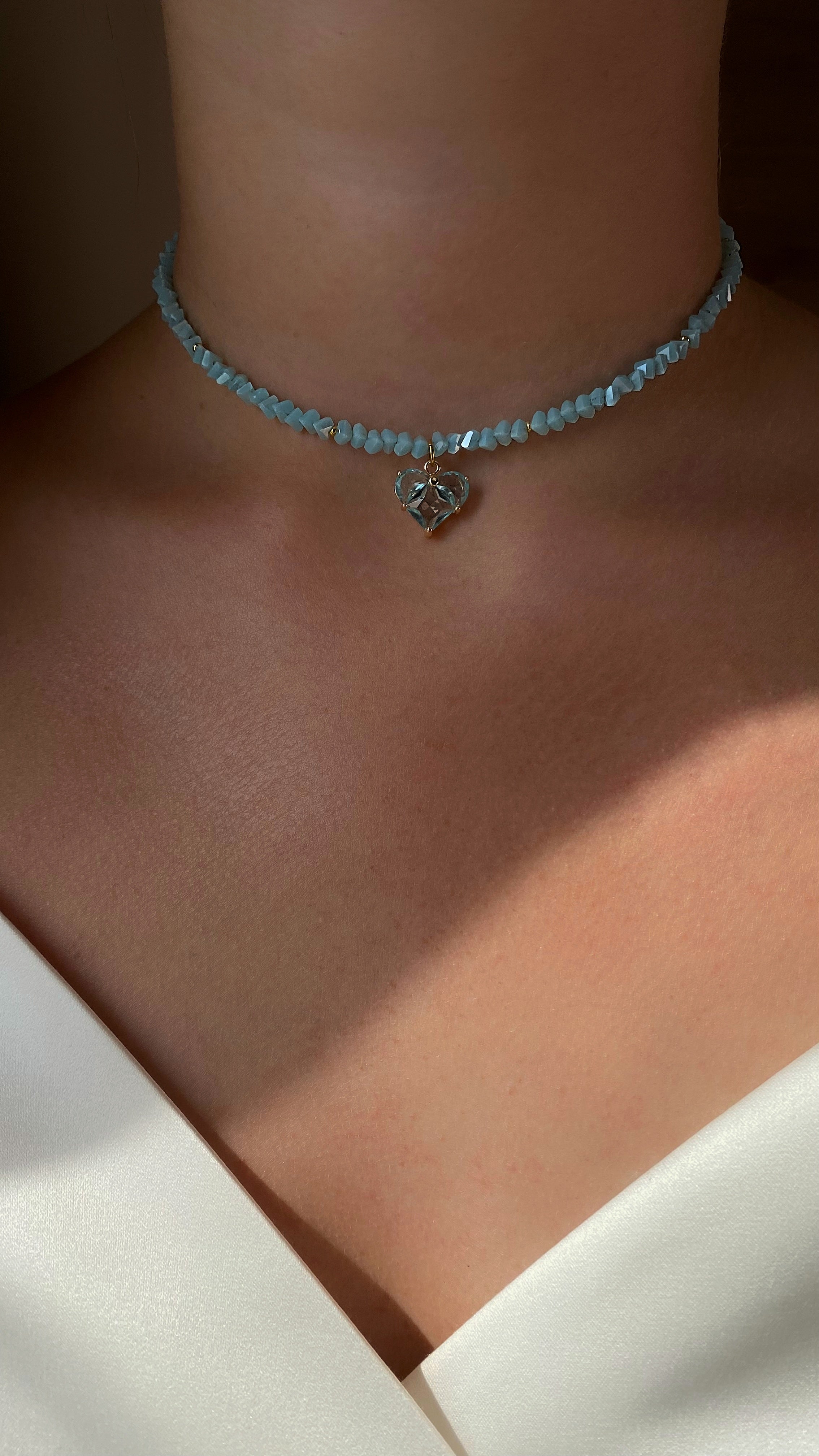 Necklace with a heart-shaped pendant on a person wearing a white garment.