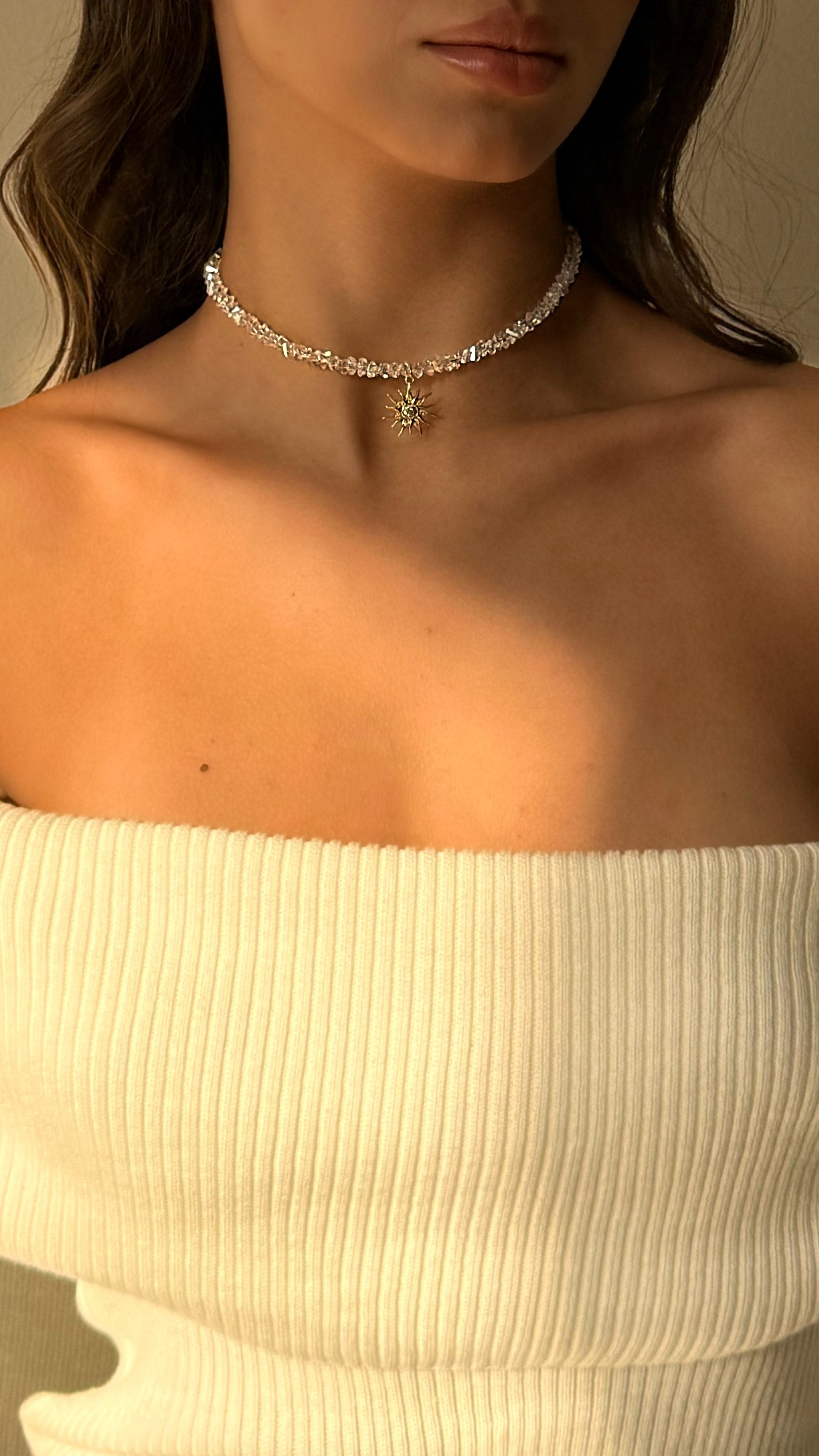 Refined choker with transparent crystal beads and a sparkling sun-shaped pendant adorned with cubic zirconia, offering elegant, modern radiance for any occasion.