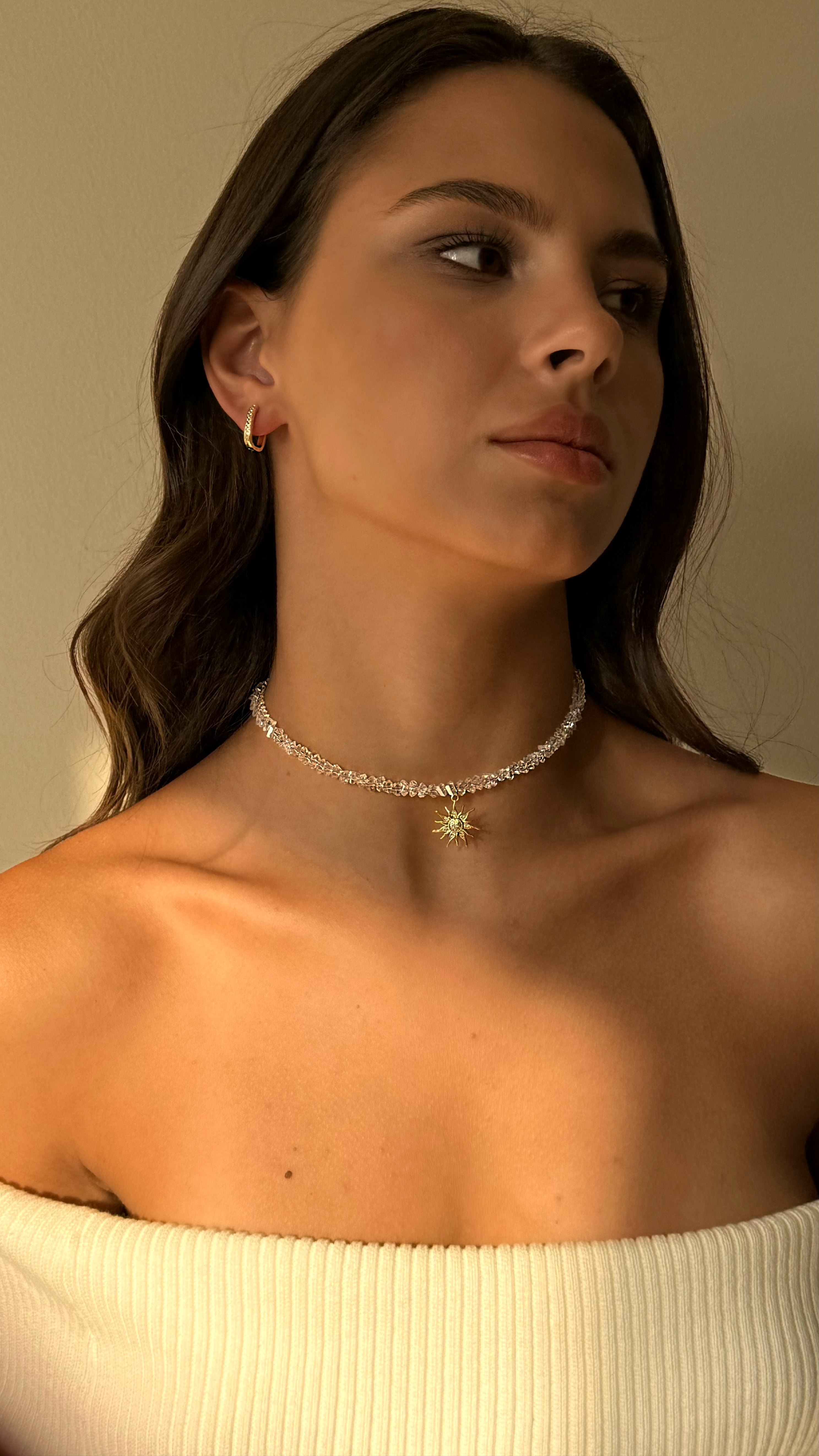 Woman wearing a delicate necklace with a neutral background