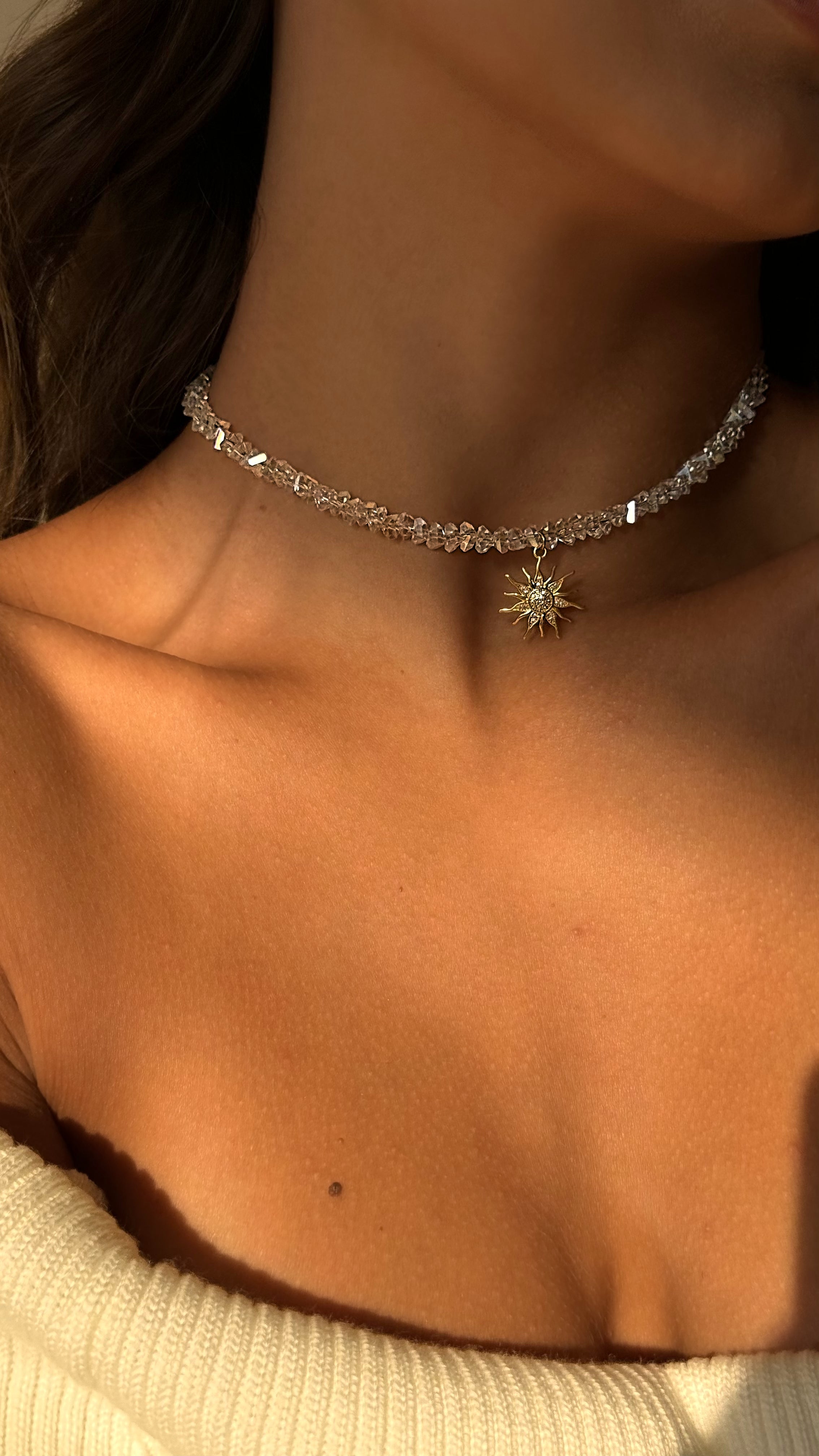 Refined choker with transparent crystal beads and a sparkling sun-shaped pendant adorned with cubic zirconia, offering elegant, modern radiance for any occasion.