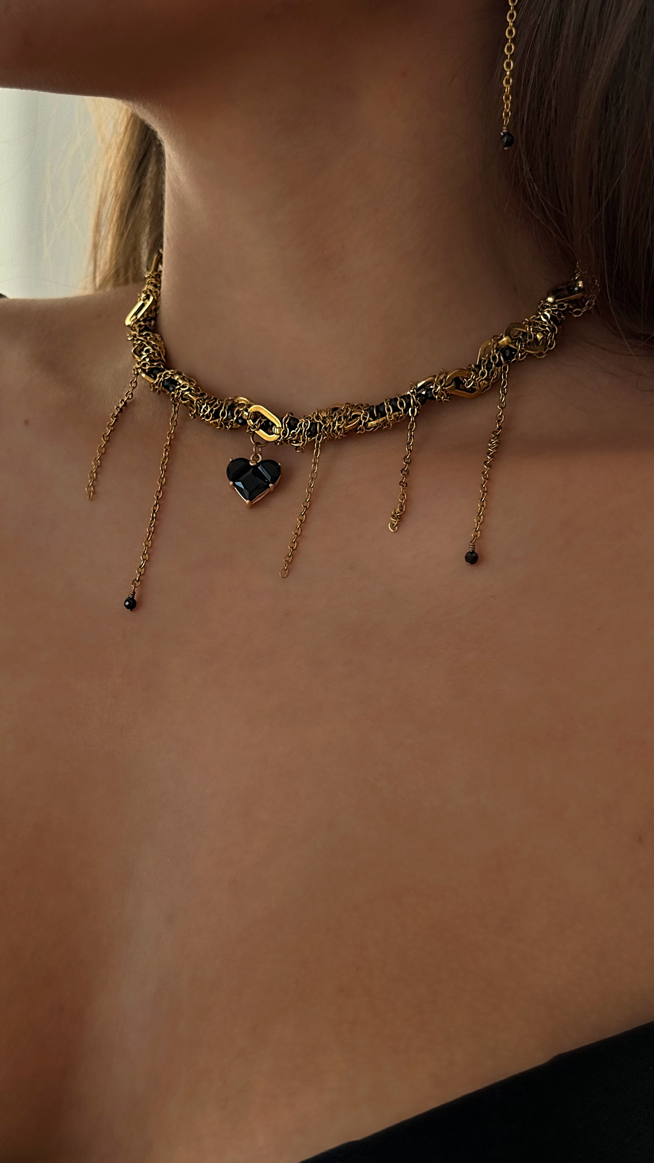 Gold plated necklace with heart-shaped pendant on a person's necke