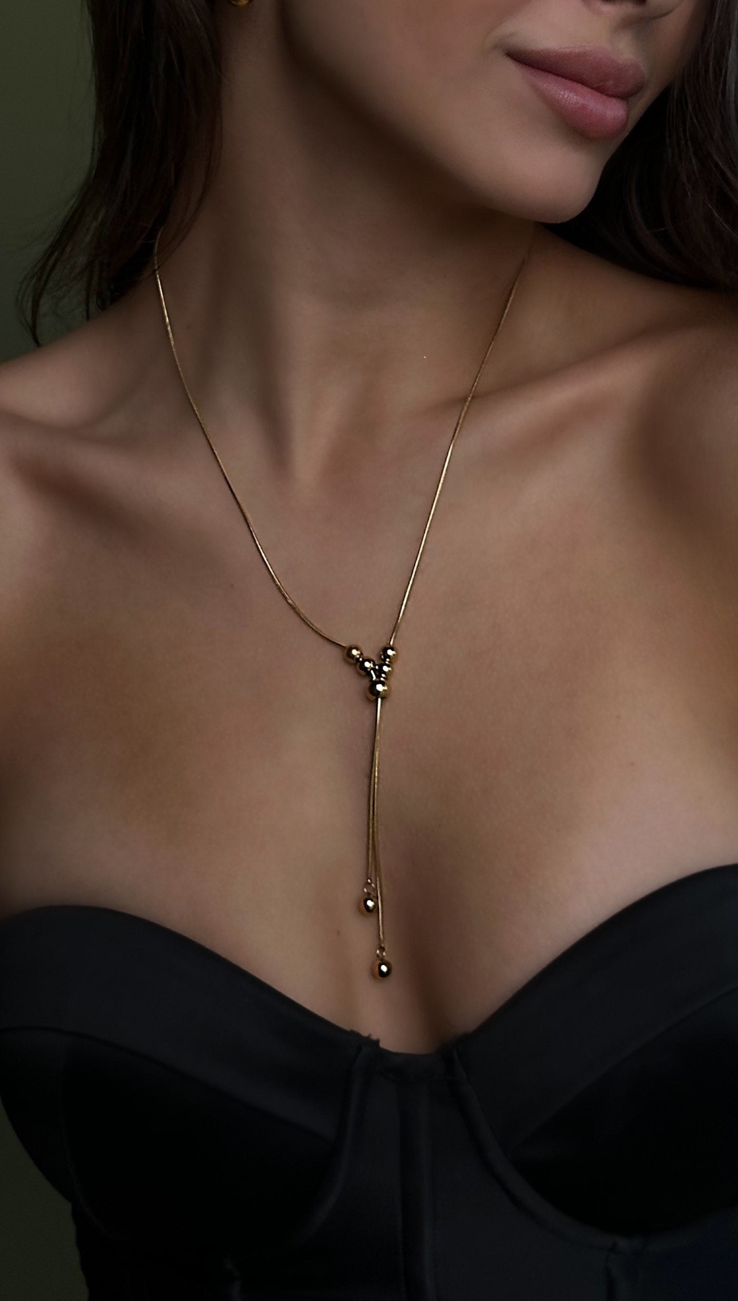 Trendy and versatile gold-tone lariat necklace with a front-facing slider, adjustable for multiple styling options, crafted from high-quality stainless steel for lasting shine.